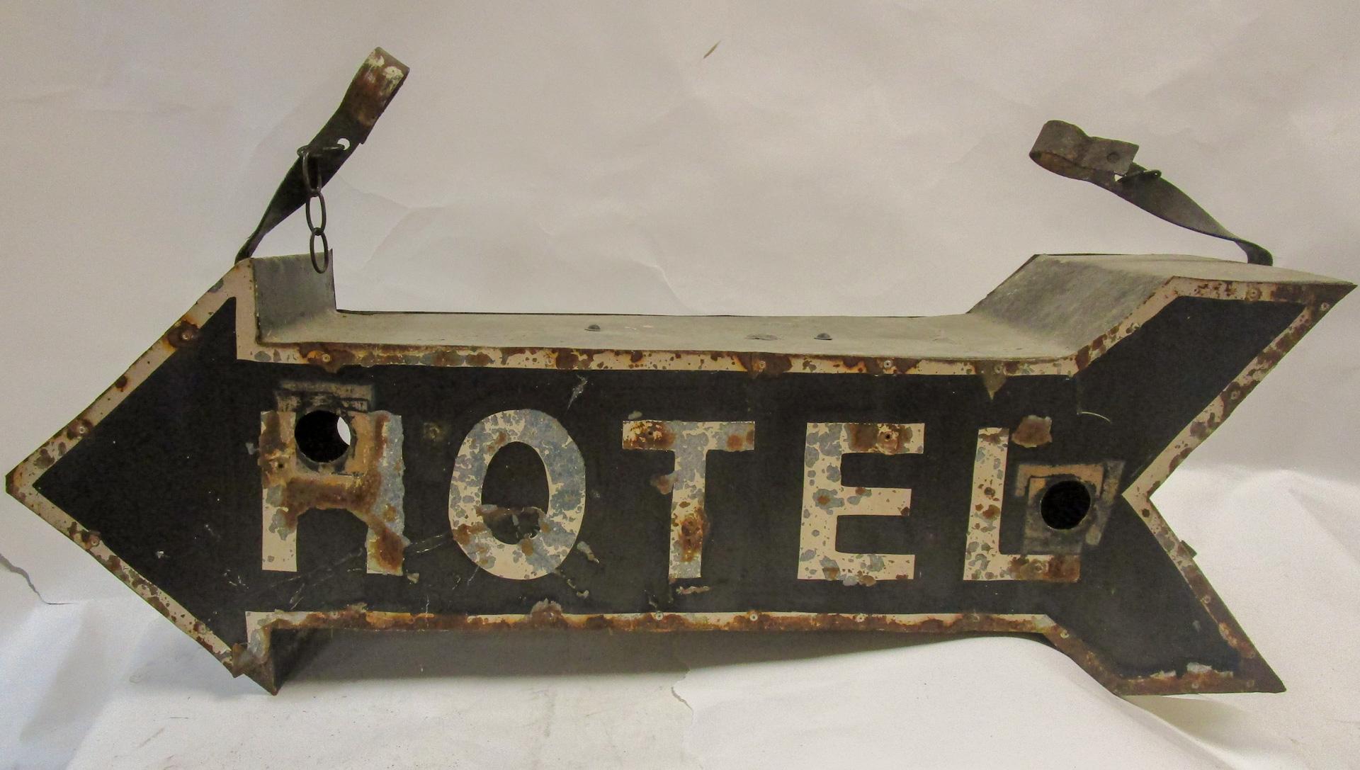 Vintage large three dimensional tin hotel sign in the shape of an arrow with a place for two light bulbs on either side. The two metal brackets add another ten inches to the piece. Retains the original blue and white paint. It is no longer