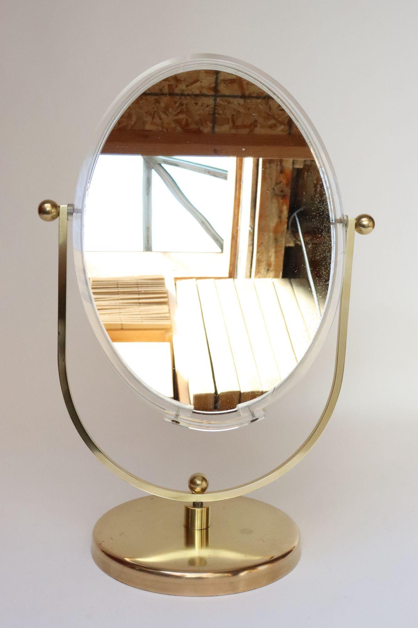 Beidseitig schwenkbarer ovaler Vintage-Spiegel von Charles Hollis Jones (ca. 1970er Jahre, USA).
Der Spiegel mit Lucite-Rand verfügt über eine 360-Grad-Drehfunktion mit Messingbeschlägen, die von einem runden Messingfuß getragen werden.
Beide