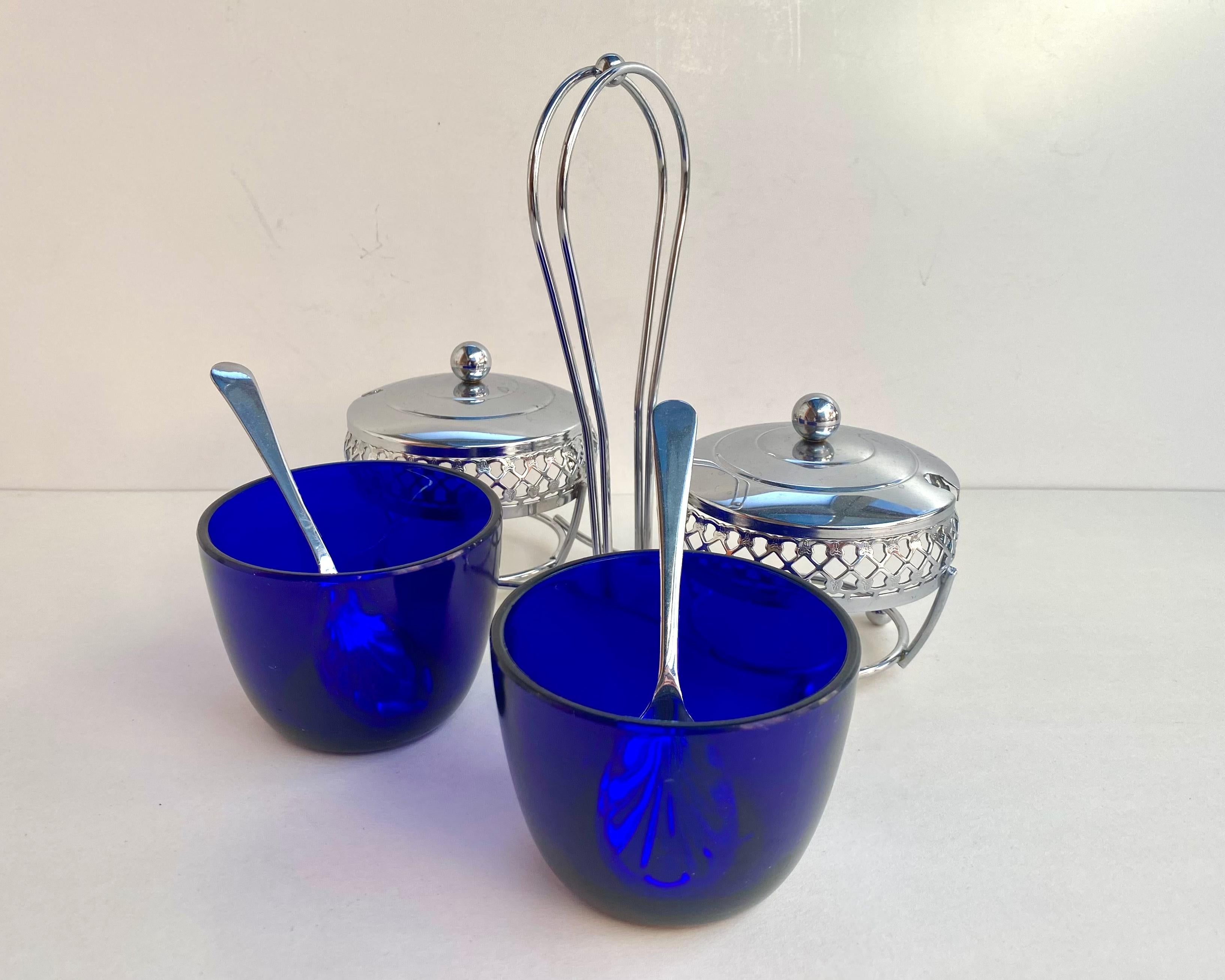 A lovely vintage cobalt blue glass sugar, jam or jelly serving dish in a metal stand with a very pretty latticework chromium plated outer casting with ornate etched handle for transporting and two spoons.

This set comes with a lid with a hole for