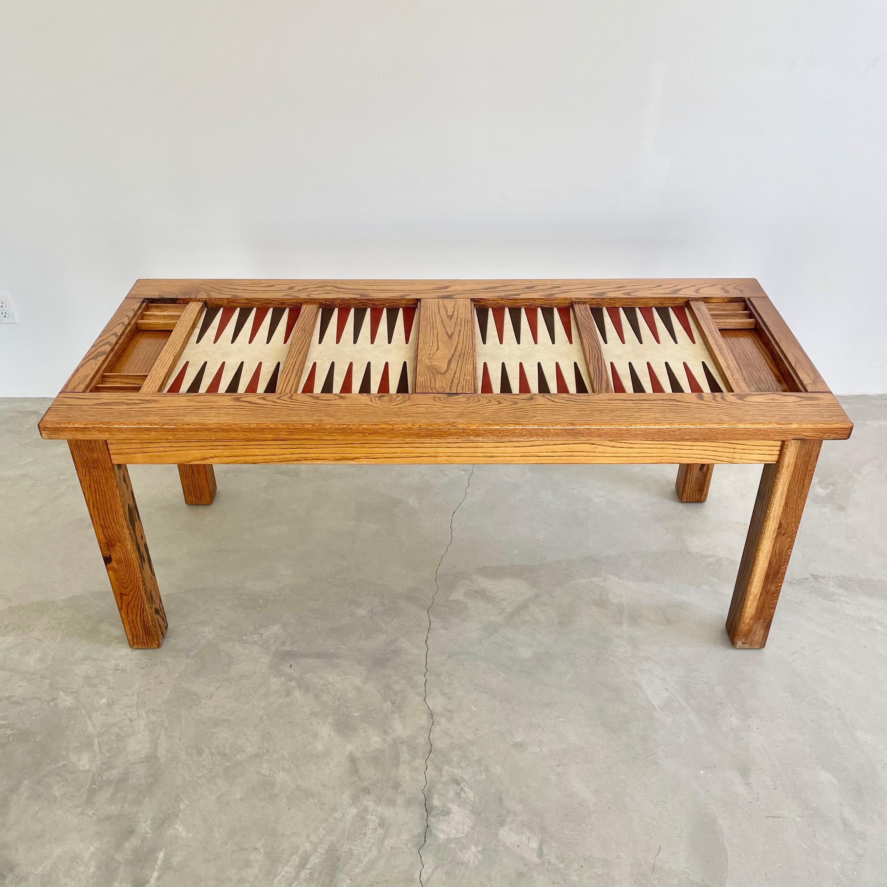 Classic oak and suede backgammon table. Unusual in that it has two playing fields. Playing surface is a cream suede with alternating burgundy and dark brown suede triangles. Chic color scheme and presence. Each side has wooden chip holders and dice