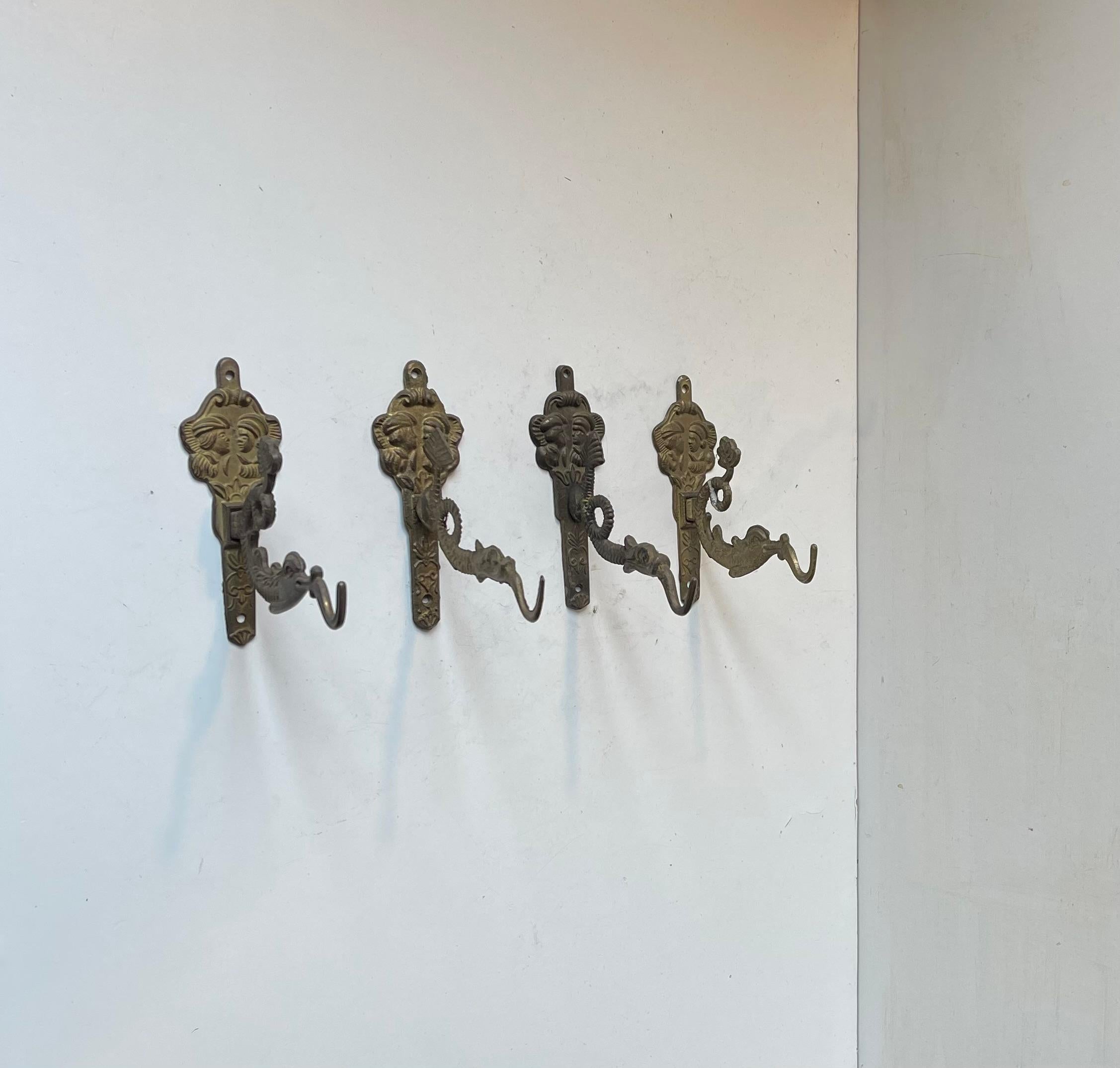 A set of 4 vintage wall hooks in brass. The hooks are made in the shape of dragons. They were cast and made in Asia between 1960-80. They have slight different features. Measurements: Dept/length: 11 cm (from the wall to the end of its tongue/fire.