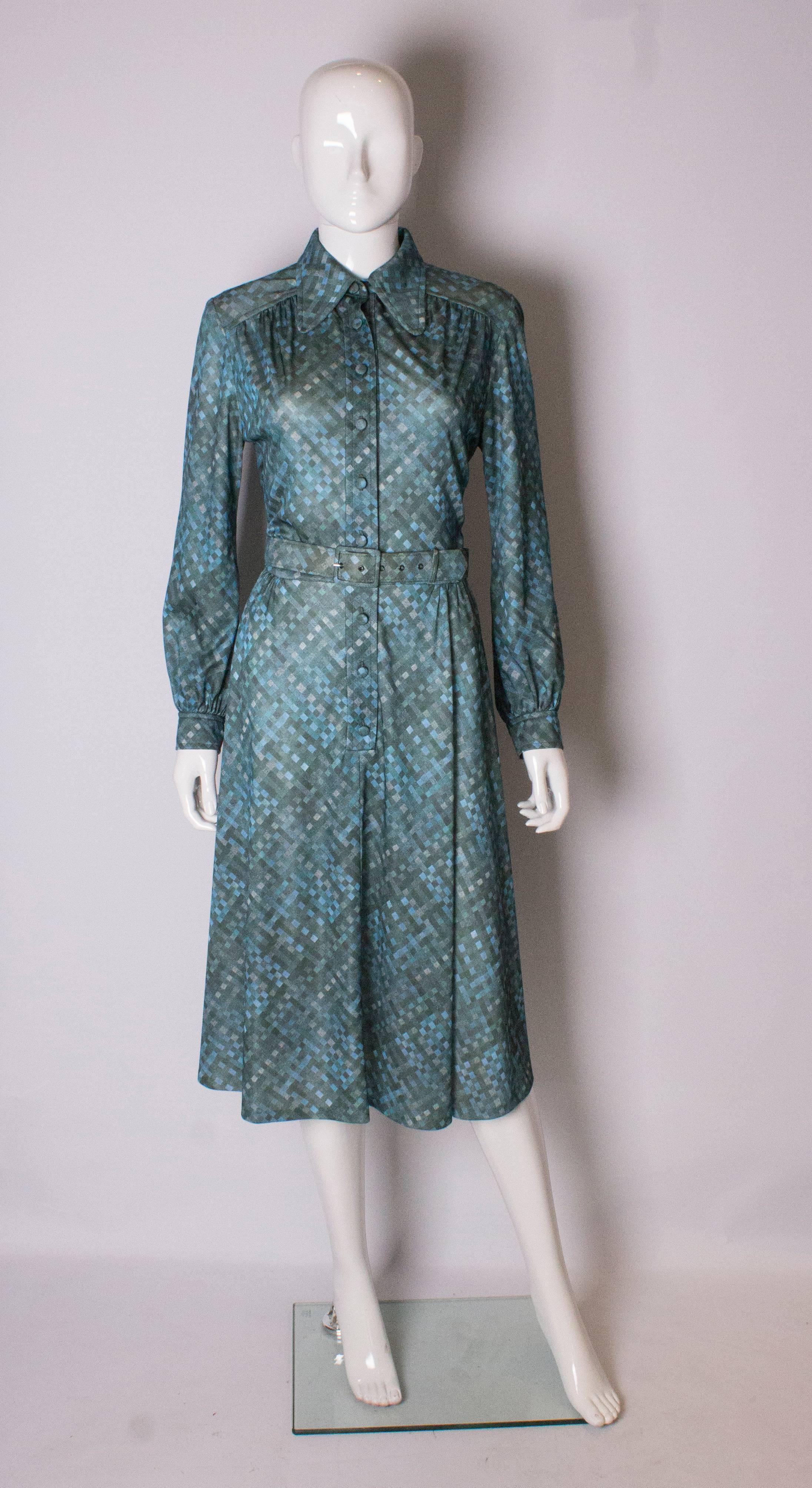 A chic dress in a great print by Carnegie of London. The dress has a front button opening with faric covered buttons, and single button cuffs. It has gathering at the waist and shoulders , self fabric belt and great collar.