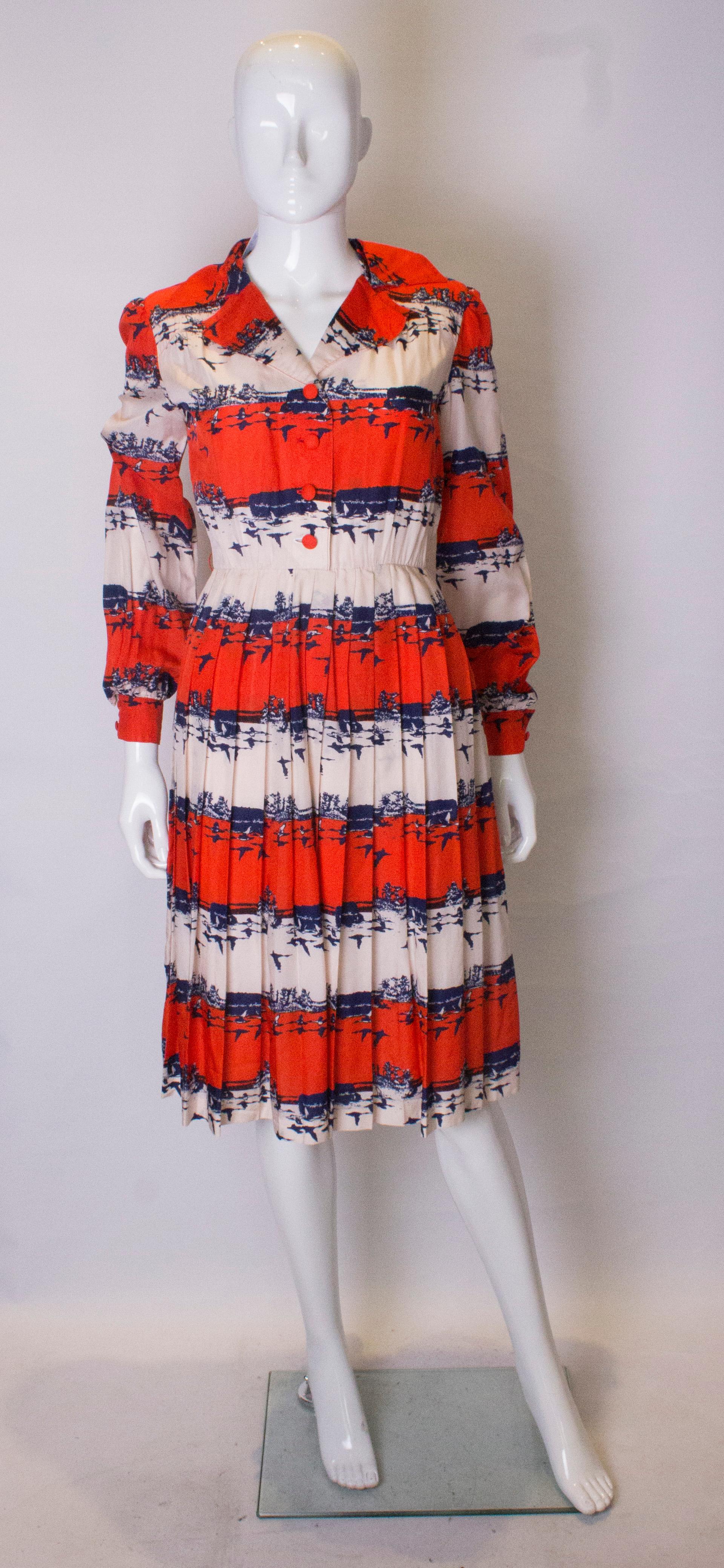 A chic, shirt dress in a red, white and blue bird print. The dress has fabric covered buttons, a popper opening at the side  and is fully lined.