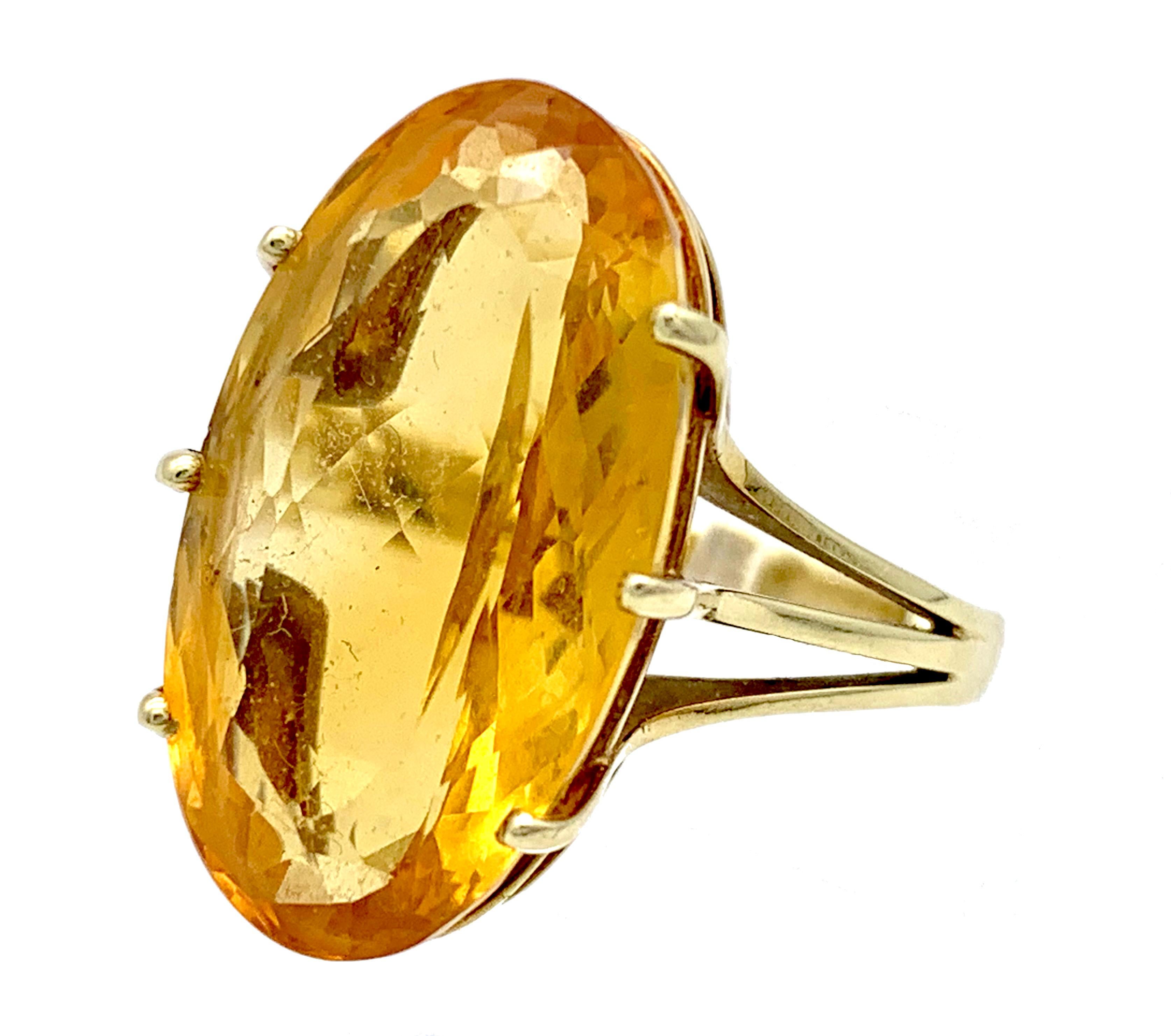 This vintage dress ring was made out of 14 karat gold is set with a large yellow gold coloured oval citrine. The shank is marked 585 for 14 karat. the oval stone is set in an open claw setting with a high gallery. The ring has had two gold balls