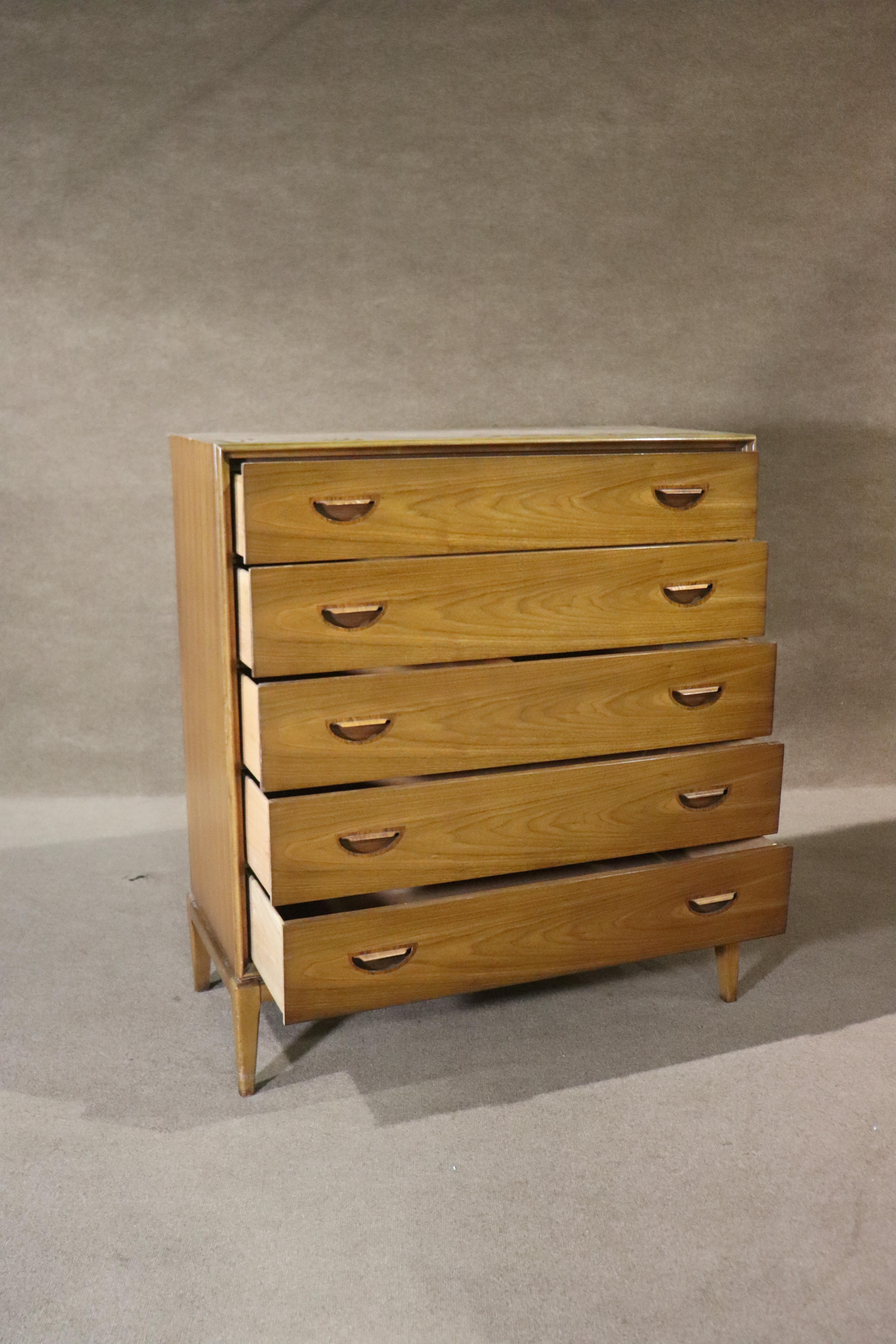Mid-century modern tall chest of drawers in stunning walnut wood grain with sculpted inset rosewood handles. Five wide drawers set on tapered legs. Very simple but unique vintage design.
Please confirm location NY or NJ