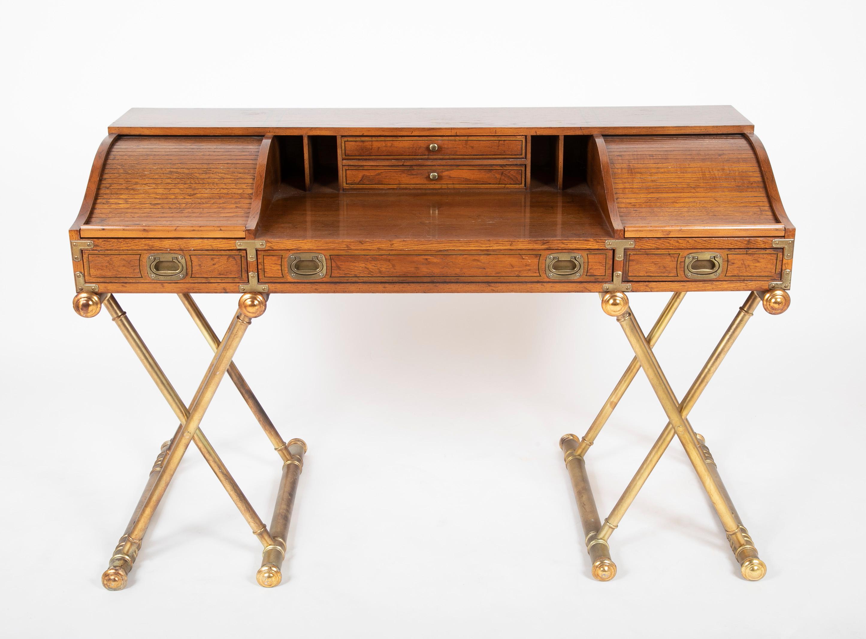 Fabulous vintage Campaign style low roll top desk with gilt X-leg base by Drexel. 
A handsome desk by Drexel, done in Campaign style with low roll tops or tambour doors on each side of the desk top which sits on a gilded X-base. It is a good sized
