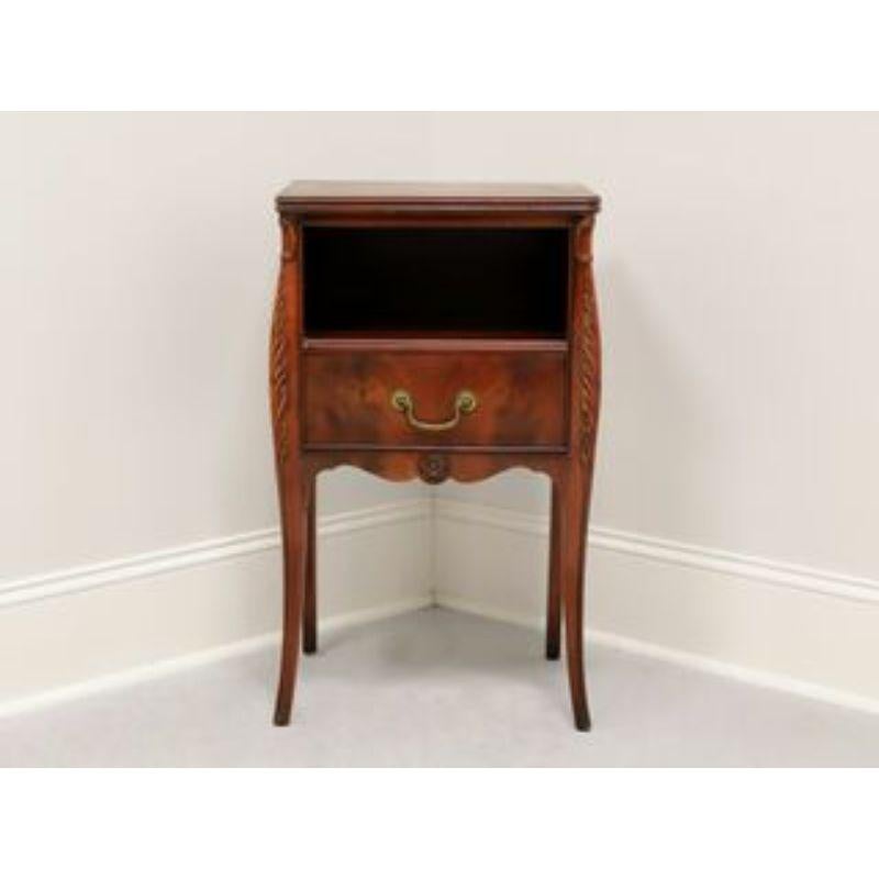 A French Provincial style nightstand by Drexel. Made in North Carolina, USA in the mid 20th Century. Flame mahogany with carved details at corners and apron. Features one dovetail drawer with brass hardware below an open storage area, both elevated