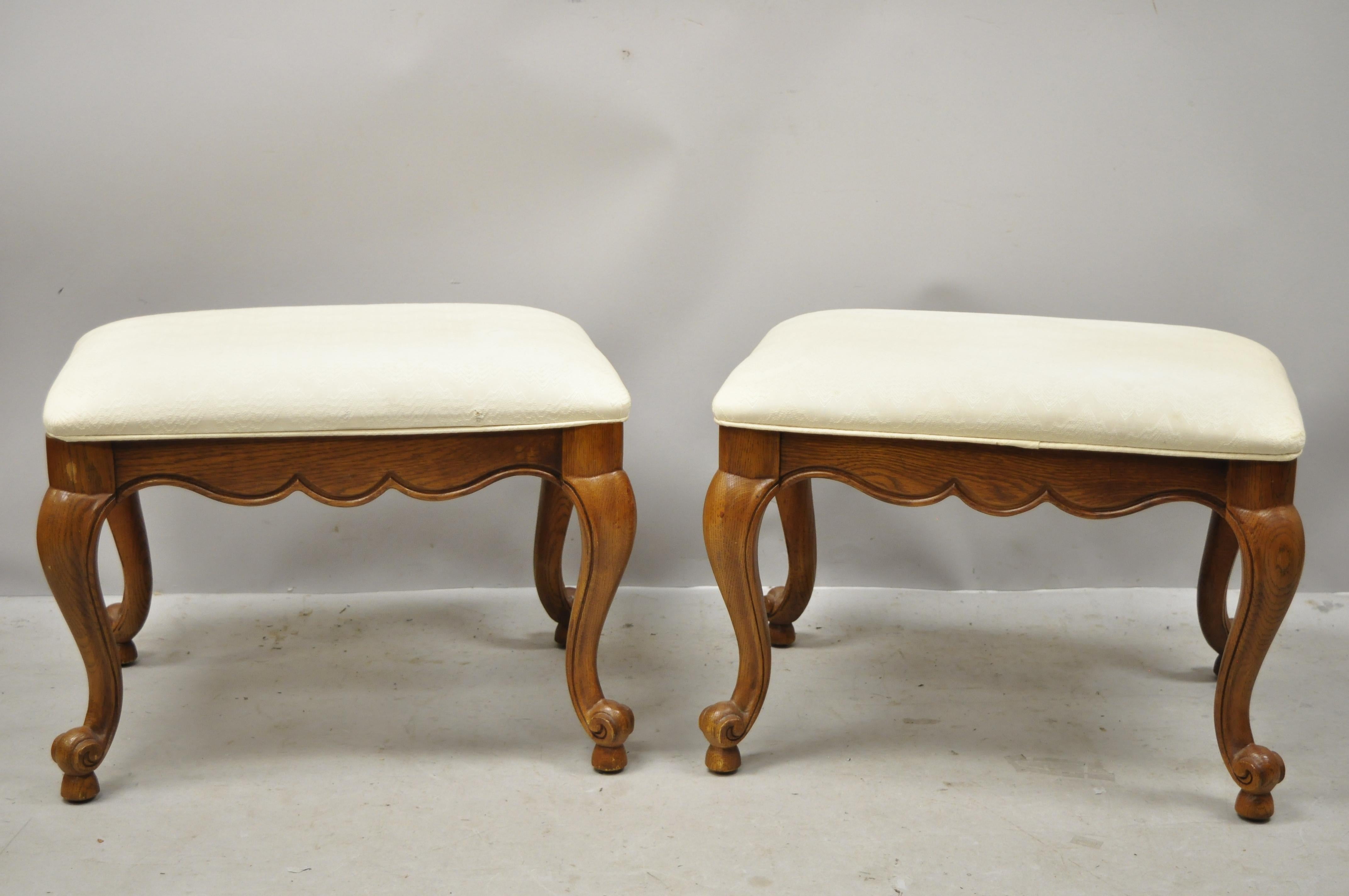 Vintage Drexel French style Provincial oakwood cabriole leg stool bench - a pair. Unmarked but believed to be by Drexel Furniture Co. Item features solid wood construction, beautiful wood grain, nicely carved details, shapely cabriole legs, quality