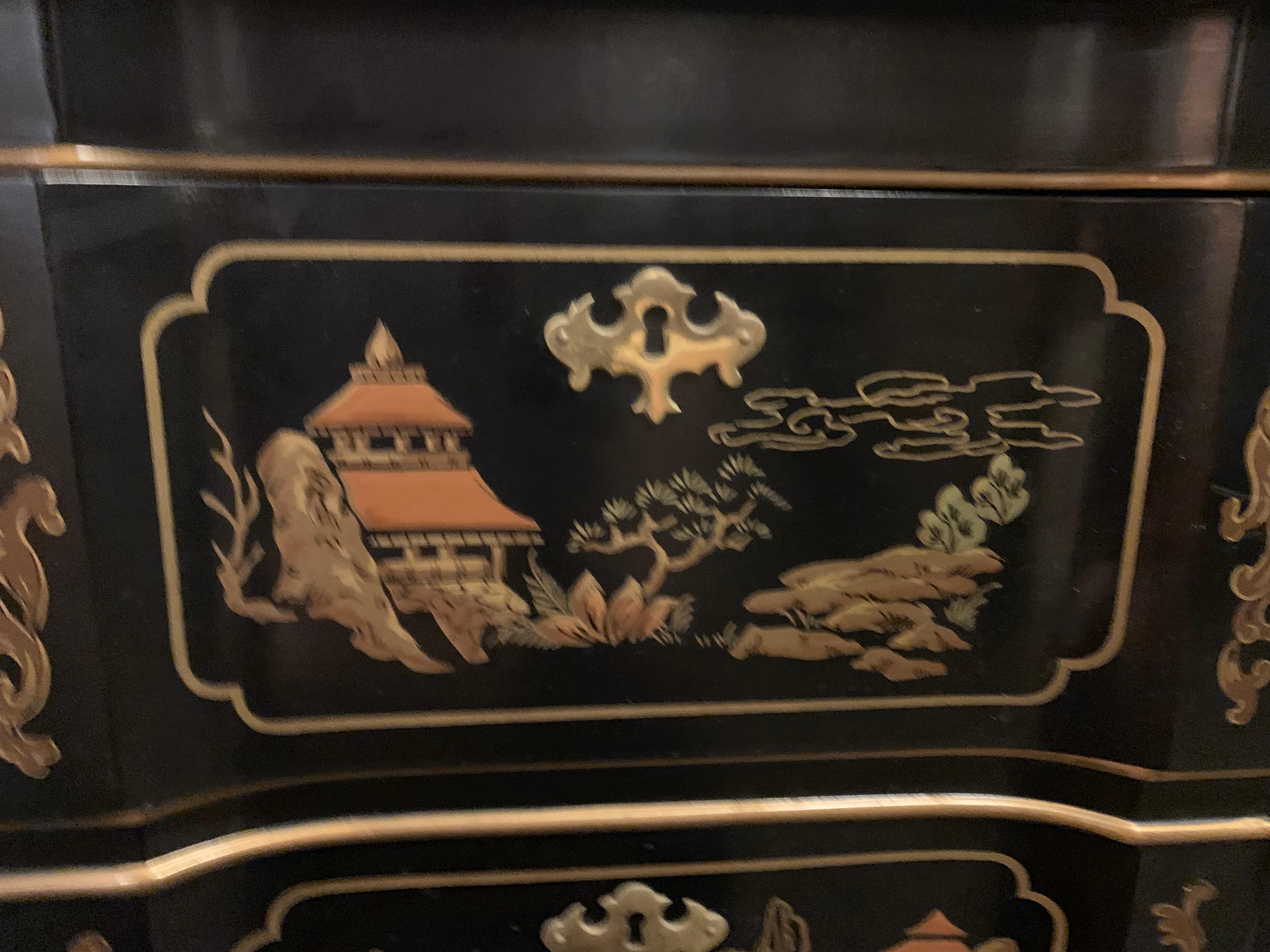 A chinoiserie style three-drawer dresser in black with gold painted accents and vignettes throughout. Drawers feature three painted scenes each and include figures, landscapes, and architectural elements. Sides of the dresser are also illustrated,