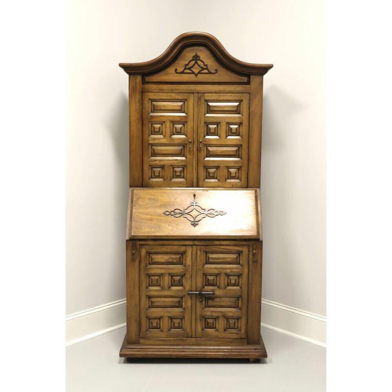 A Mediterranean style secretary desk by Drexel Heritage, from their Et Cetera Collection.Solid oak with brass accents and hardware. Upper has dual door blind bookcase with two adjustable wooden shelves. Lower is slant front, has drop down desk