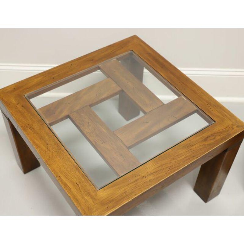 A pair of campaign style glass top square coffee / cocktail tables by Drexel Heritage, from their Woodbriar Collection. Pecan wood with geometric design pattern and glass top. Made in North Carolina, USA, in the mid 20th century.

Measures: 23.75 W