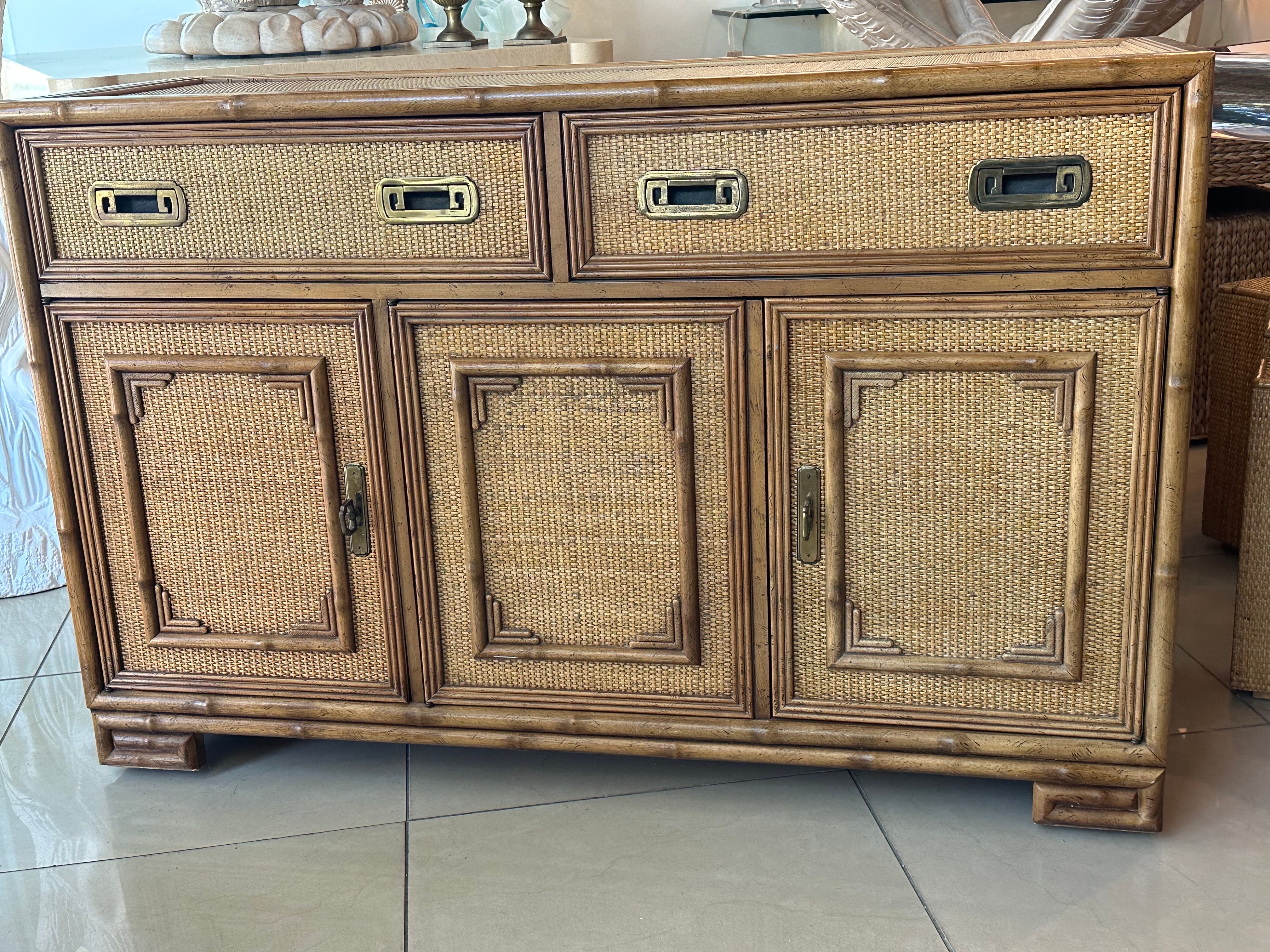 Beautiful vintage Drexel bamboo, wood, rattan, woven cane wicker, brass cabinet credenza buffet dresser. Comes with inset glass top. 2 drawers, 3 doors. One side has a shelf. There is no damage or issues to this well taken care of piece. Dimensions: