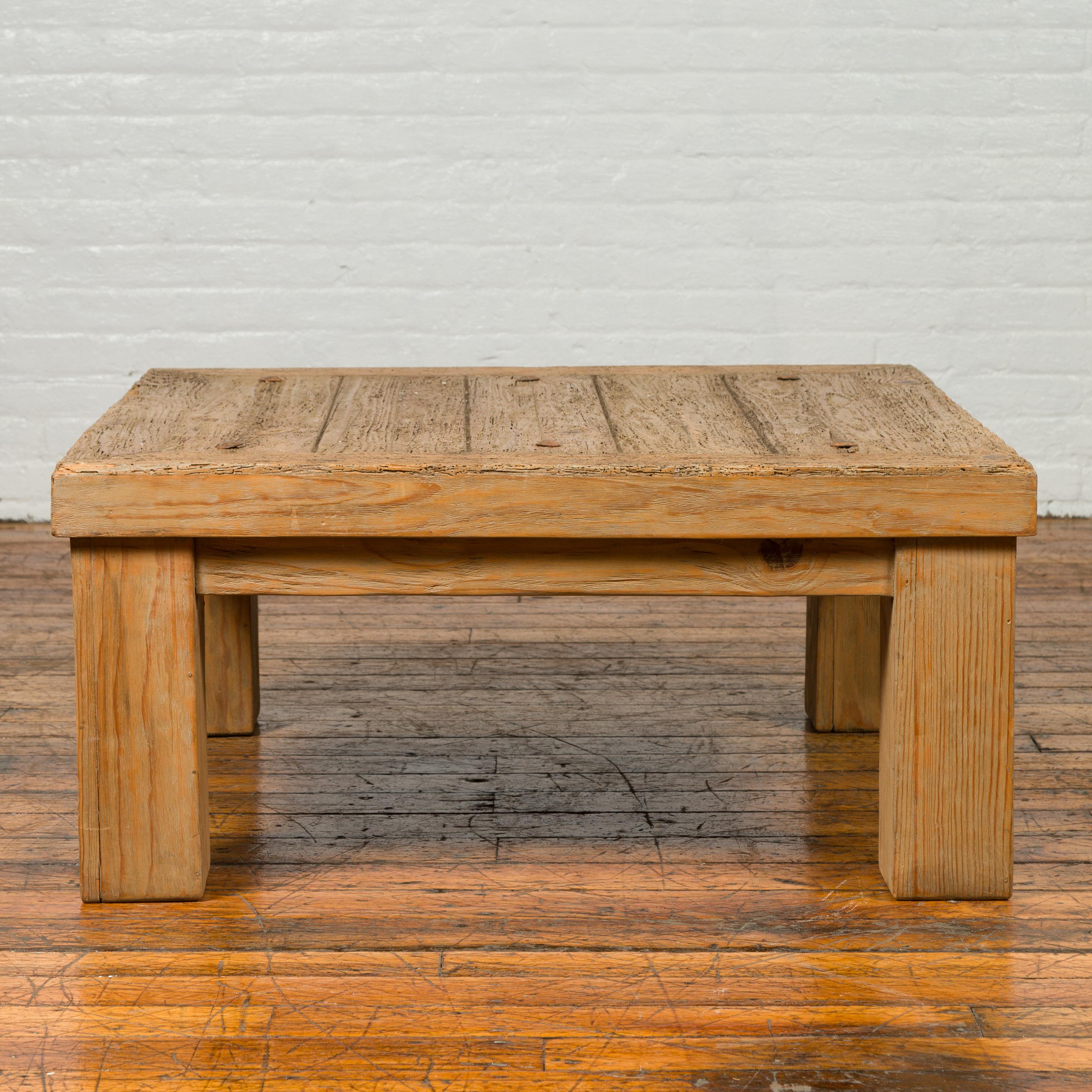 A vintage driftwood distressed coffee table from Mexico with round metal studs and square legs. Born in Mexico during the midcentury period, this driftwood coffee table charms our eyes with its clean lines and rustic appearance. Featuring a