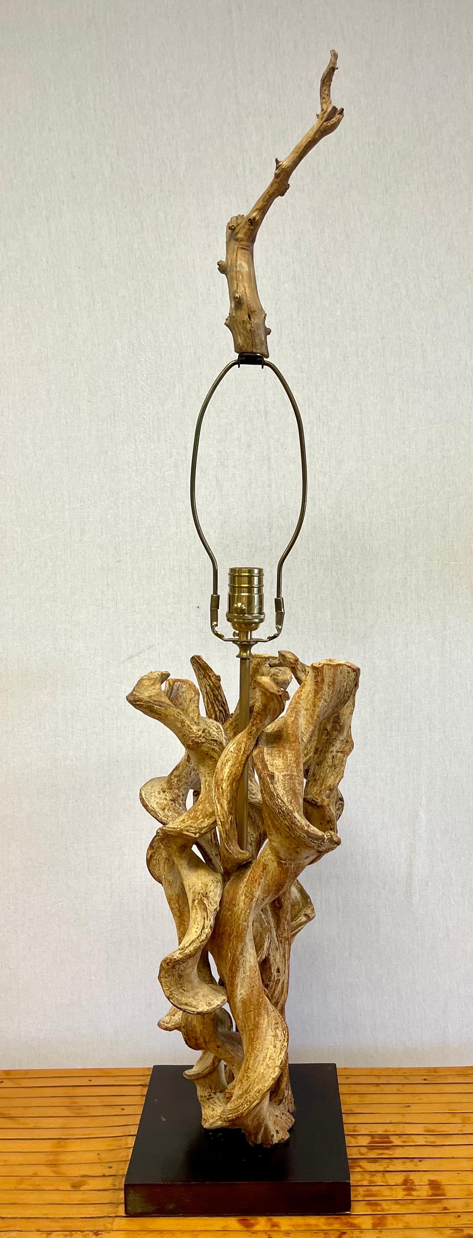 Vintage sculptural driftwood lamp made of intertwining branches and topped with matching finial. Mounted on a lacquered wood base.
19”H to top of socket.