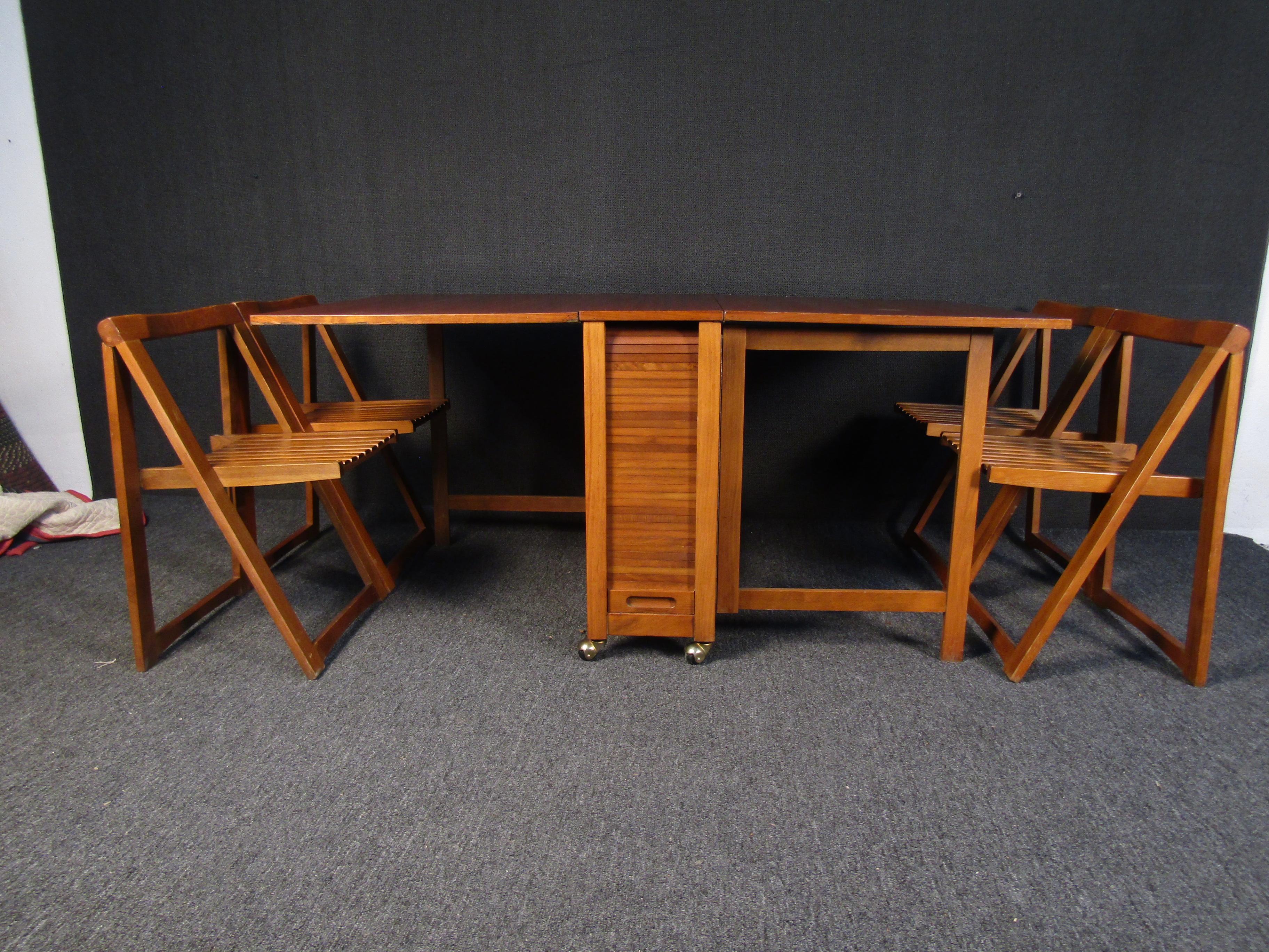 A vintage rolling drop leaf table with four folding chairs that stow away inside the table. With a design that allows one or either side to be folded down, this versatile dining room set can work in a large or smaller space. 
Please confirm item