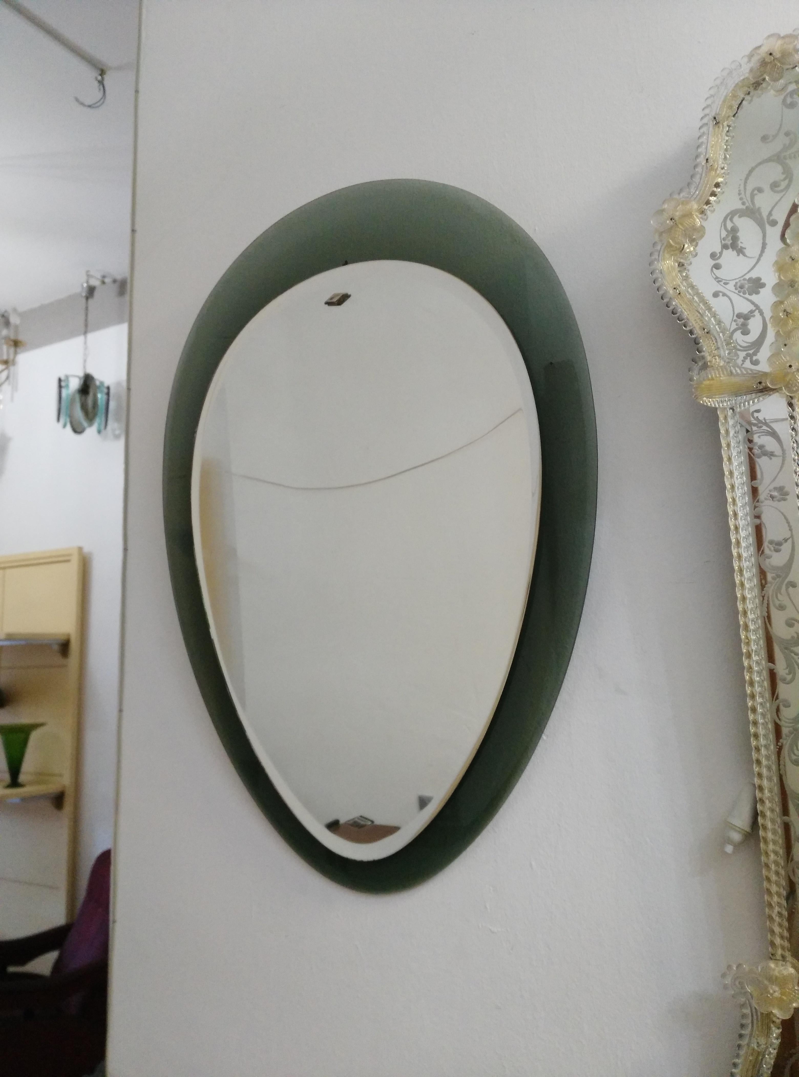 Wall mirror with a particular shape as it represents a drop, the part surrounding the mirror is in green colored glass.
Produced in Italy in the Mid-century