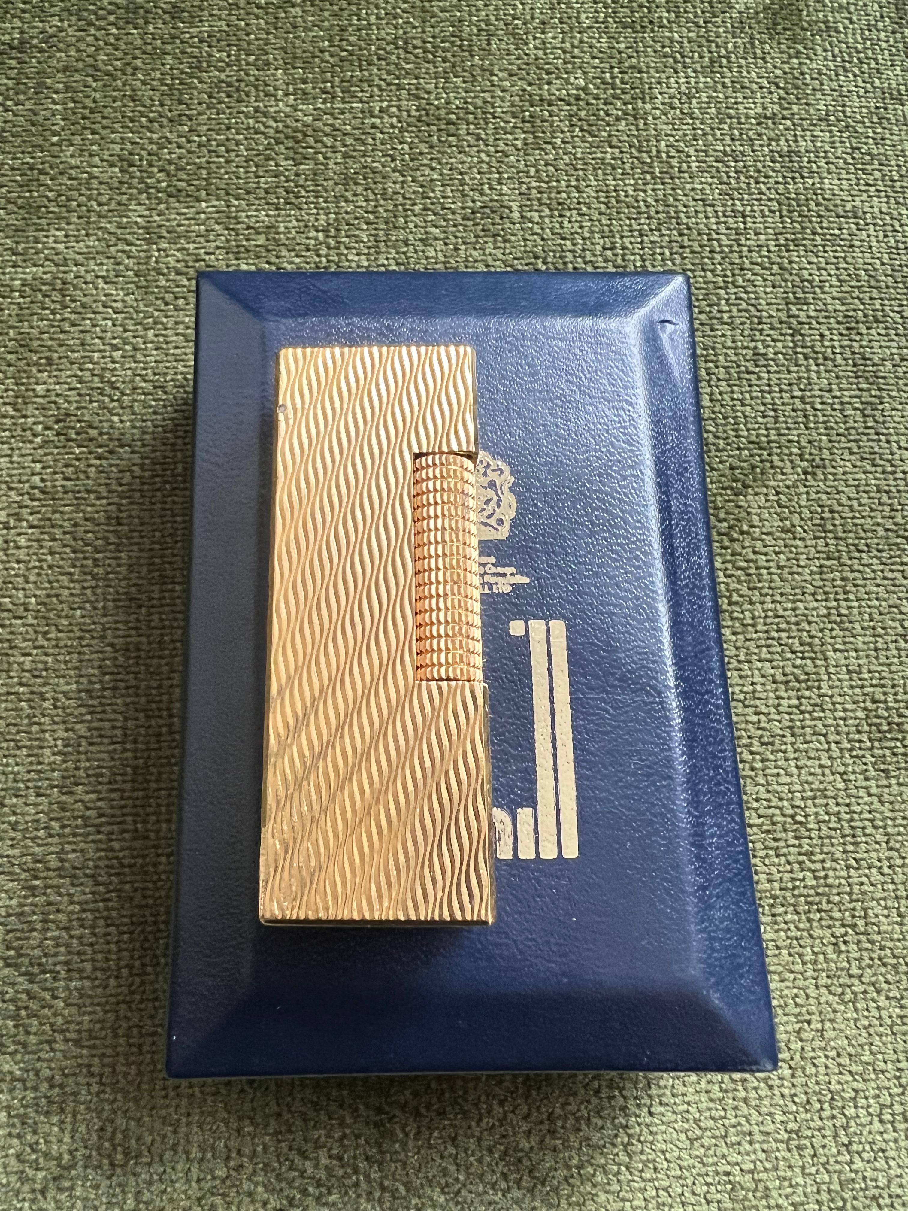 Rare Iconic Vintage and Elegant Dunhill Gold Swiss Made Lighter. 
As seen in the James Bond film. 
Dunhill gold plated Swiss Made lighter In mint condition. 
Works perfectly.  
Rare wave pattern 
Iconic and beautifully engineered piece in rare