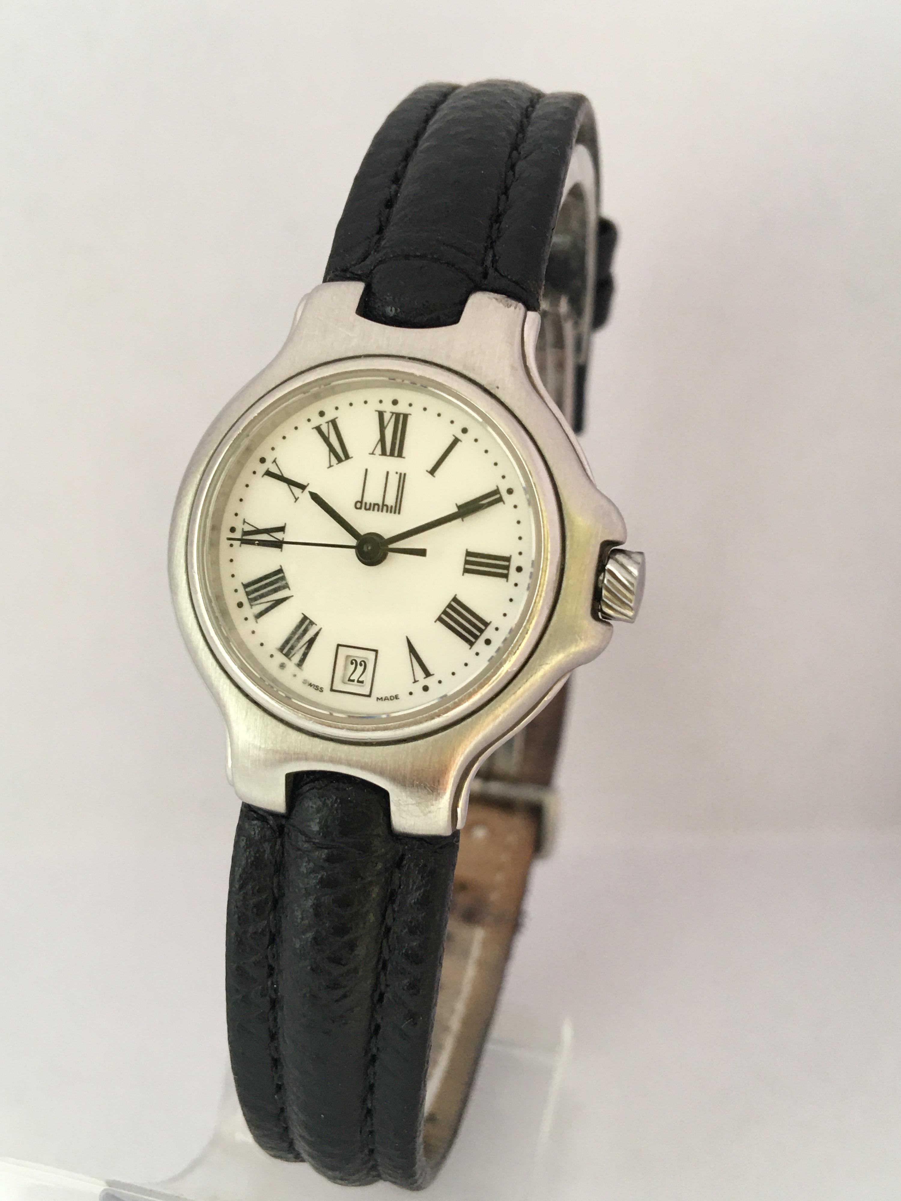 Dunhill stainless steel lady's wristwatch, case no. 84 10093, circular white dial with Roman numerals, dot minute markers, date aperture at the six position and centre seconds, quick set date, Dunhill black leather strap and deployment clasp,
