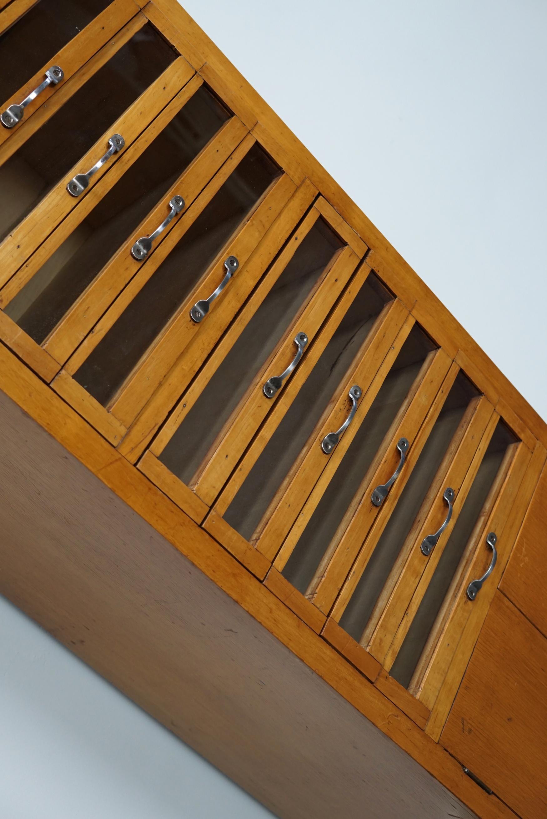 This haberdashery cabinet was produced during the 1950s in the Netherlands. This piece features 10 drawers in light beech with glass fronts and metal handles. It was originally used in a shop for sewing supplies and fabrics in Amsterdam. The