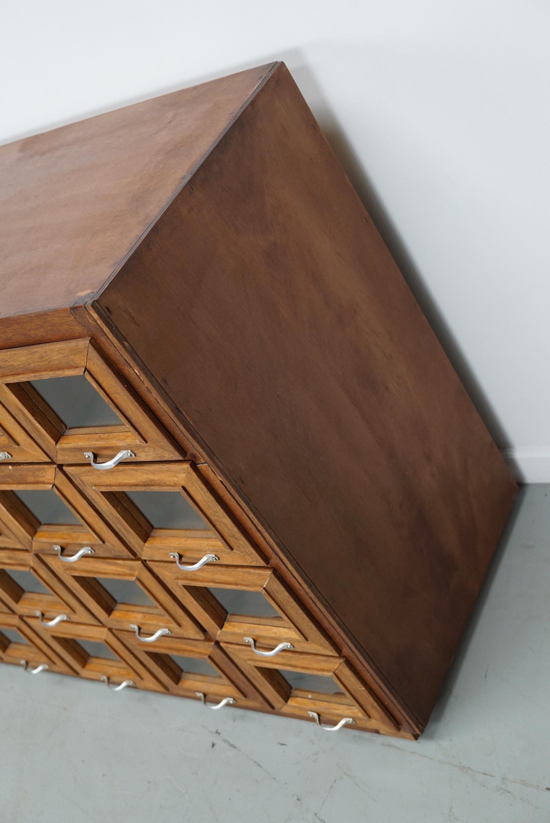This haberdashery cabinet was produced during the 1950s in the Netherlands. It features 36 drawers in beech with glass fronts and metal handles. It was originally used in a warehouse for plant seeds in the city of Delft. The top is made of plywood