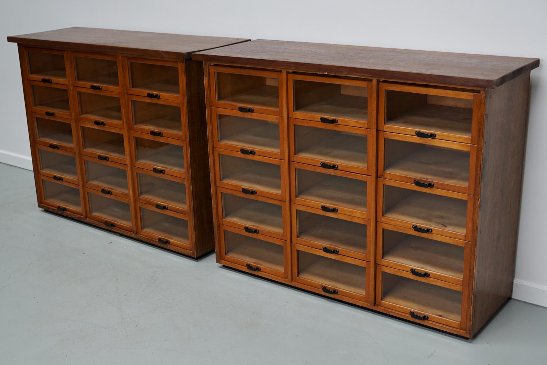 This haberdashery cabinet was produced during the 1950s in the Netherlands. It features 15 drawers in beech with glass fronts and metal handles. It was originally used in a warehouse for plant seeds in the city of Delft. The interior dimensions of