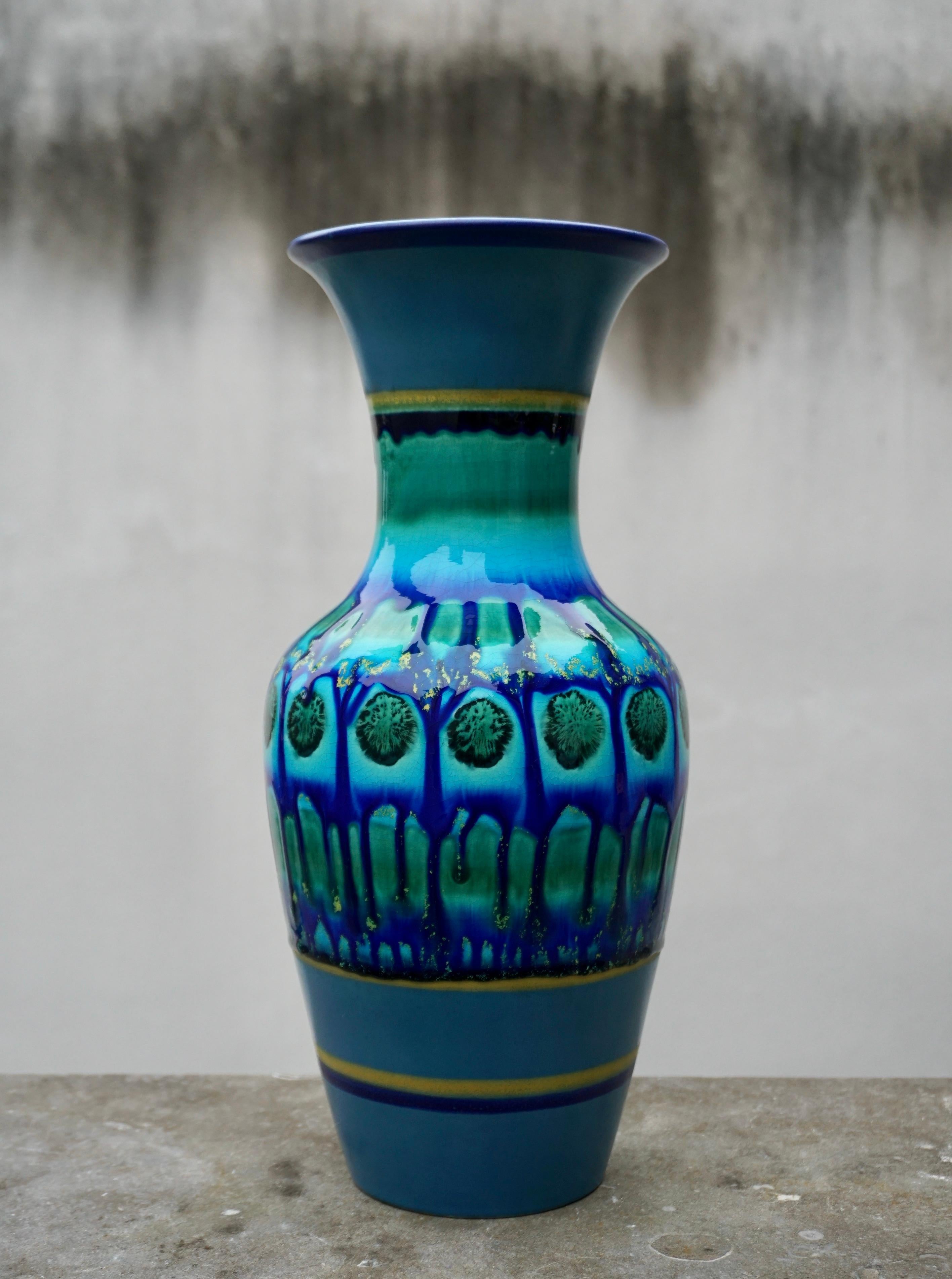 Vintage blue ceramic fat lava style vase marked on base: Flora Holland.
Hand Painted.  

Flora Holland - Gouda porcelain factory circa 1945 - 1980.  
Gouda is a generic term describing pottery produced in Gouda, The Netherlands and brightly colored