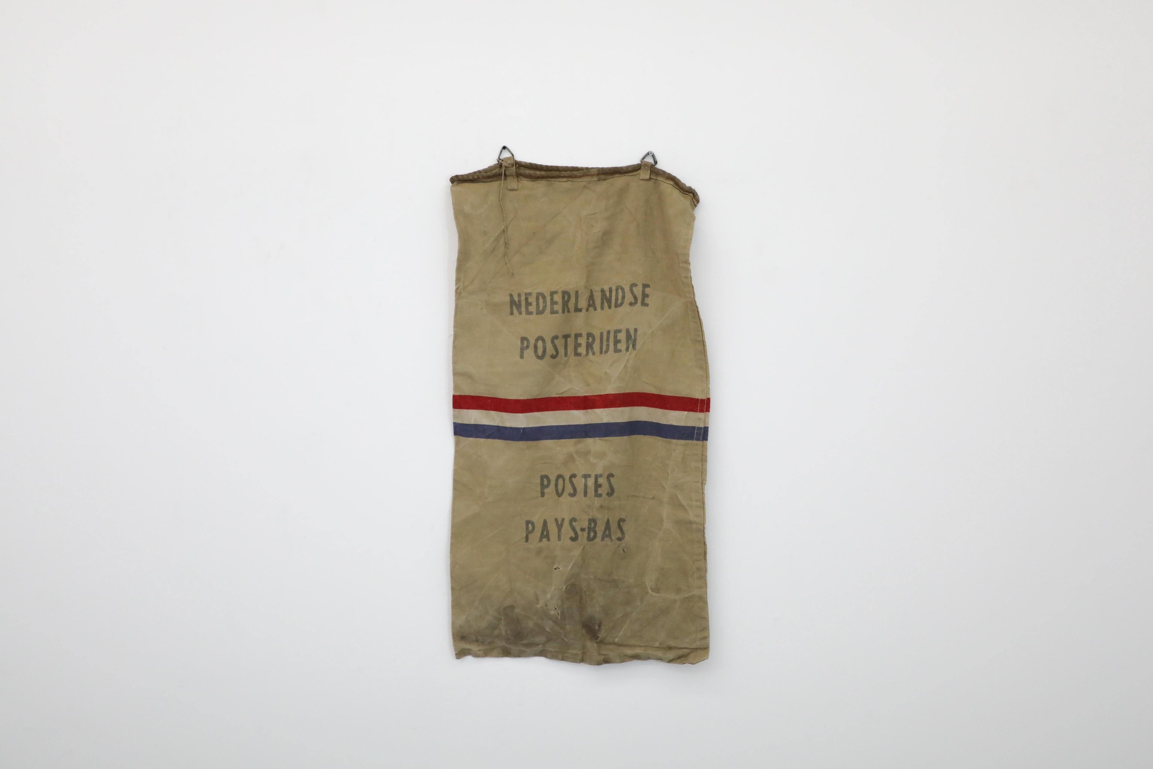 Vintage canvas postal bag with steel loops. 'Dutch Postal Service' stamped in Dutch and French hints that this piece is likely associated with shipments to bilingual Belgium. This well worn authentic postal bag makes for a stylish and historic