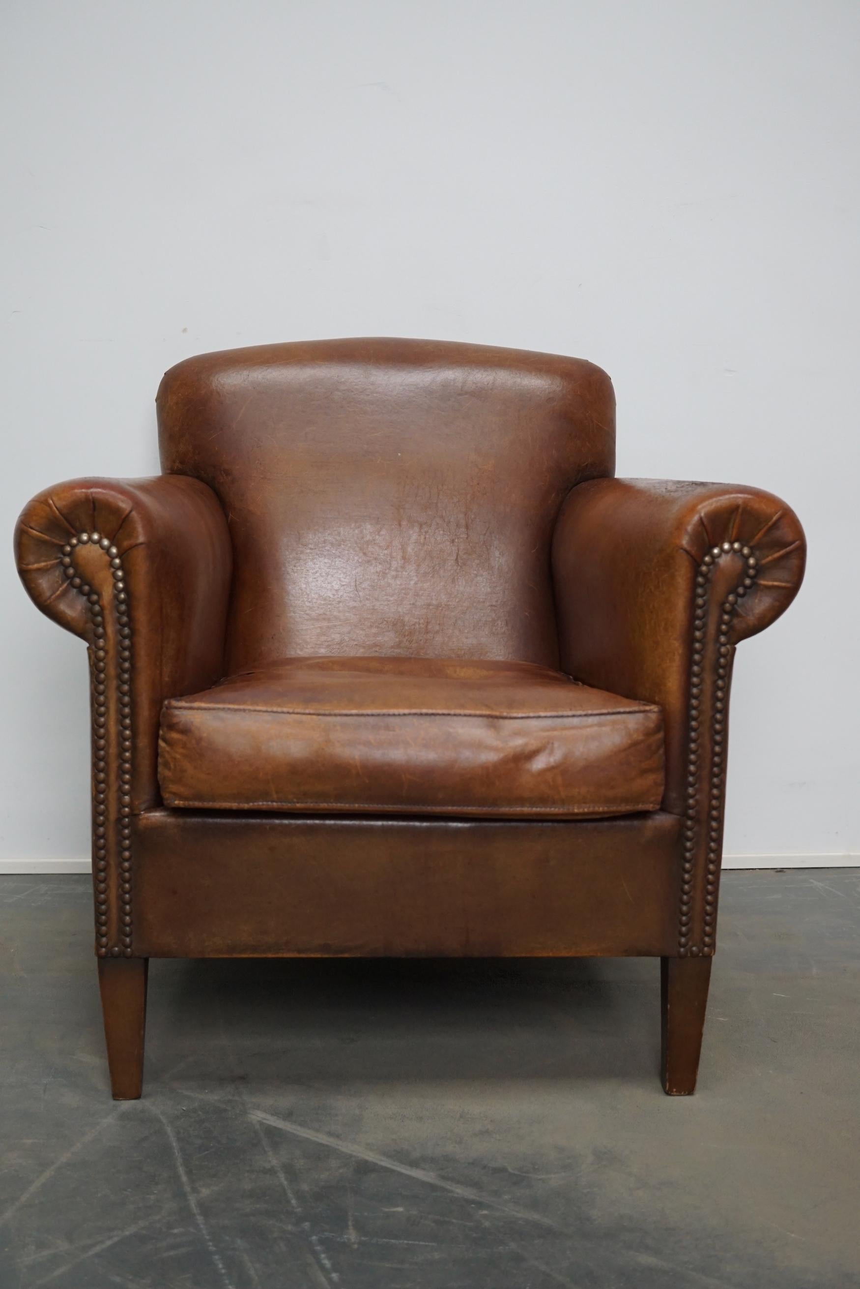 This vintage club chair is upholstered with cognac-colored leather and features metal rivets and wooden legs.

 