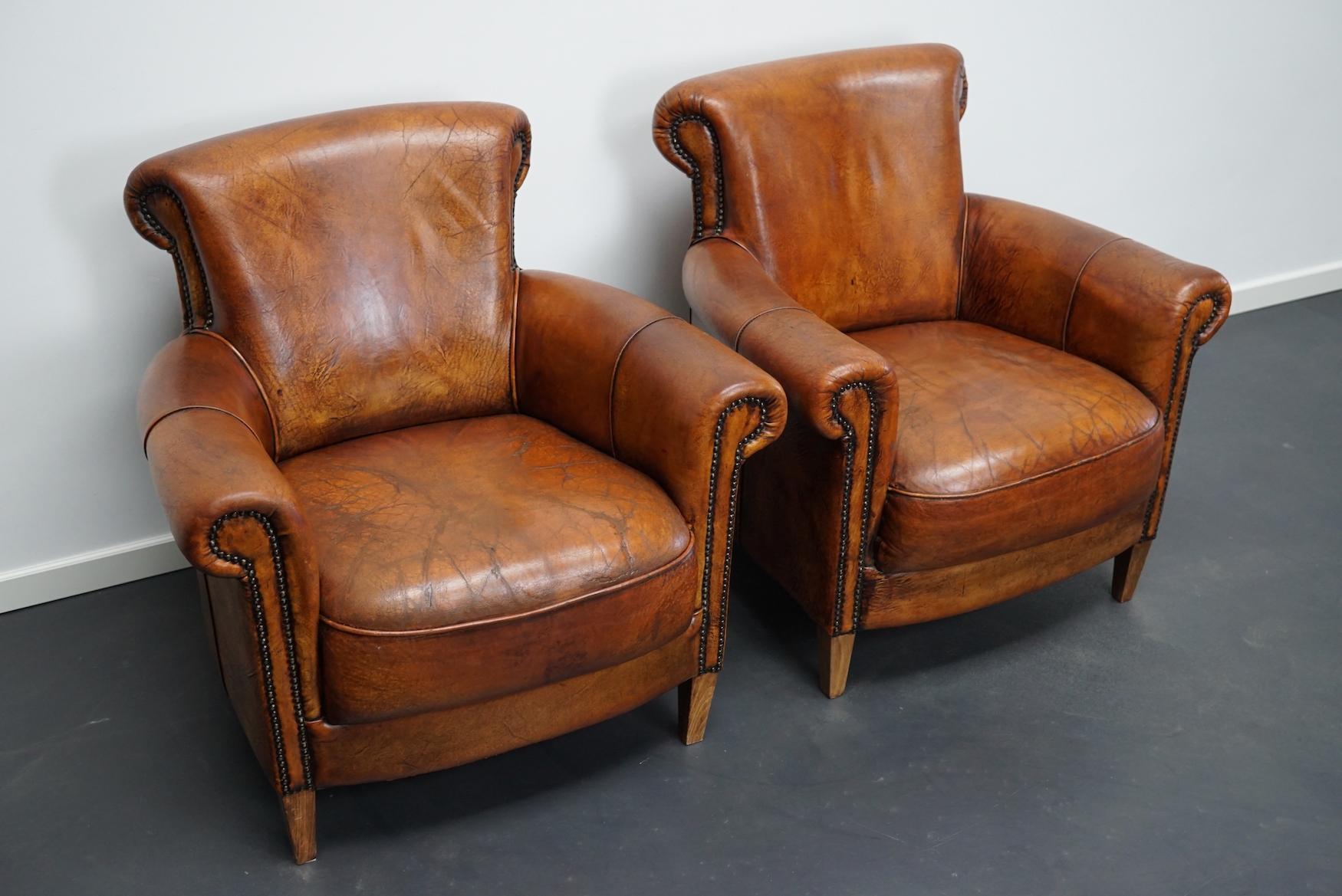 This pair of cognac-colored leather club chairs come from the Netherlands. They are upholstered with cognac-colored leather and feature metal rivets and wooden legs.
Details.
 