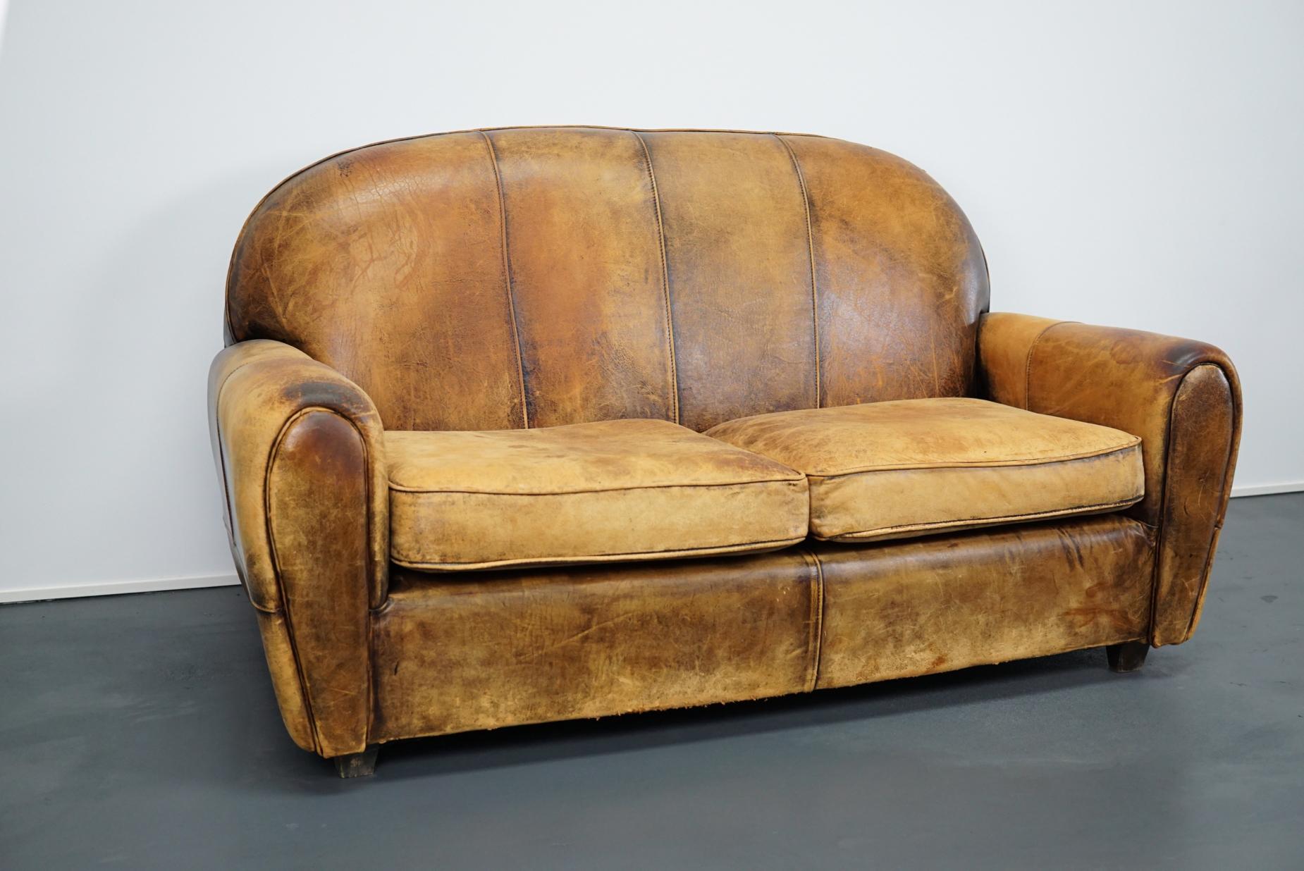 This cognac sheeps leather sofa was designed and handmade in the Netherlands. It retained a rich patina and is very comfortable. It remains in a good vintage condition.