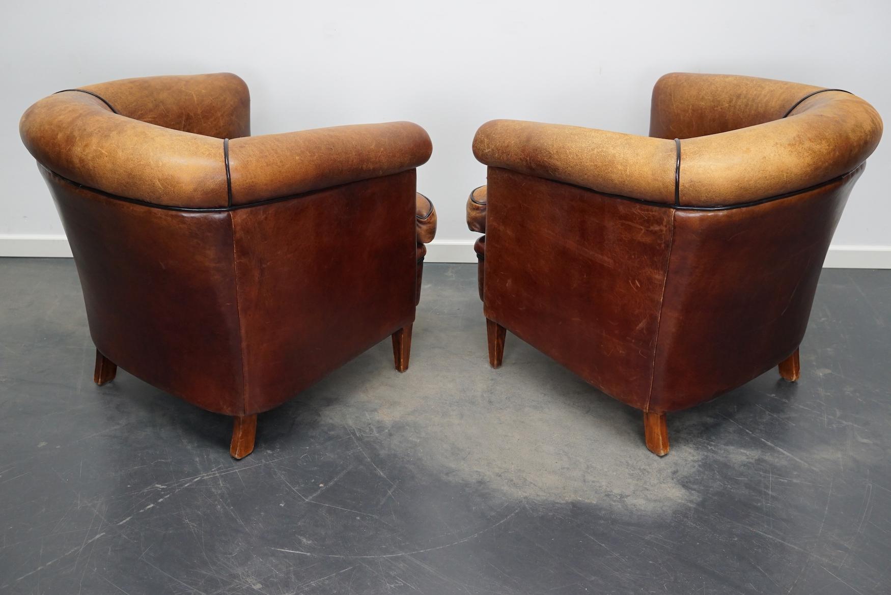 This pair of cognac-colored leather club chairs come from the Netherlands. They are upholstered with hand patinated leather and feature nails and wooden legs.