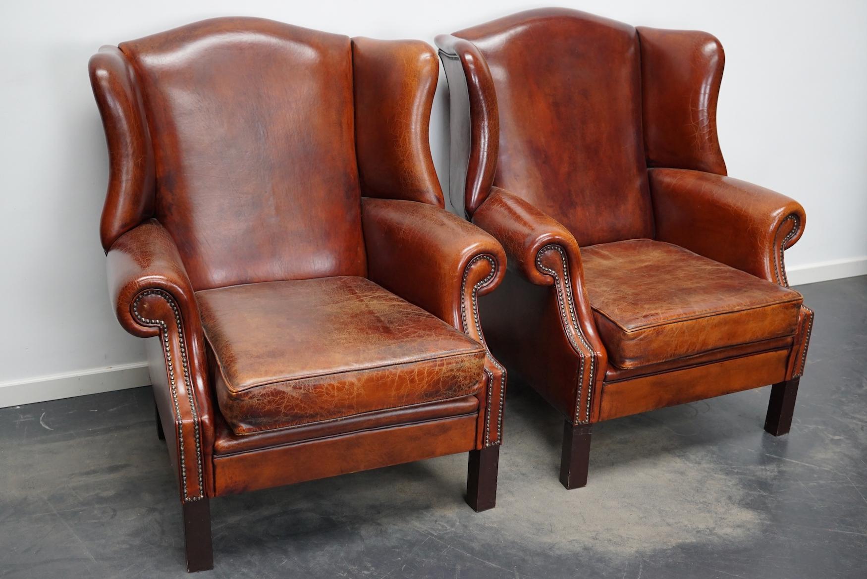 This pair of cognac-colored leather club chairs come from the Netherlands. They are upholstered with hand patinated leather and feature nails and wooden legs.