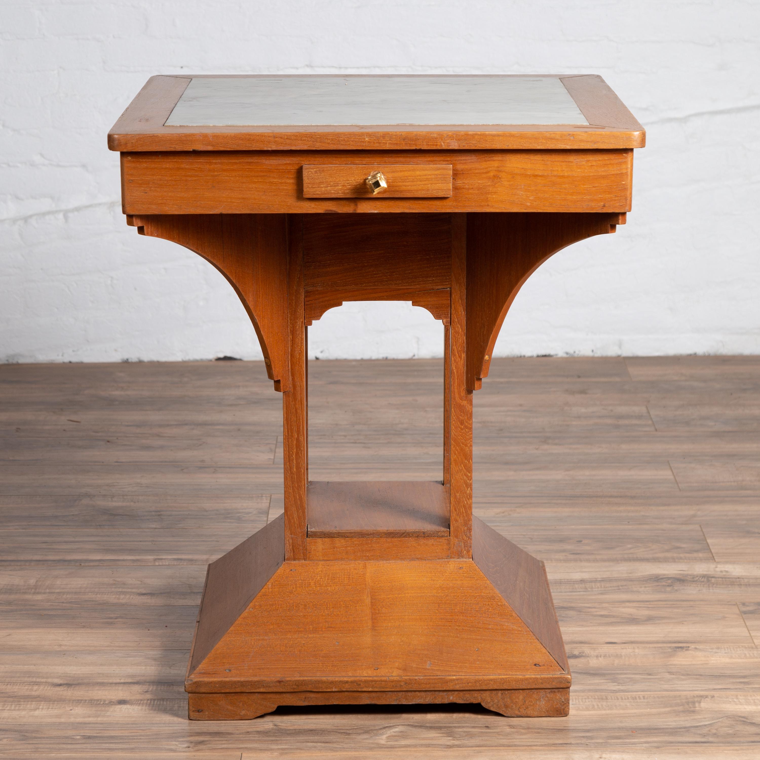 A Dutch Colonial vintage Indonesian square center table from the mid-20th century, with marble inset. Born in Indonesia during the midcentury period, this elegant center table features a square top with white veined marble inset. The apron,