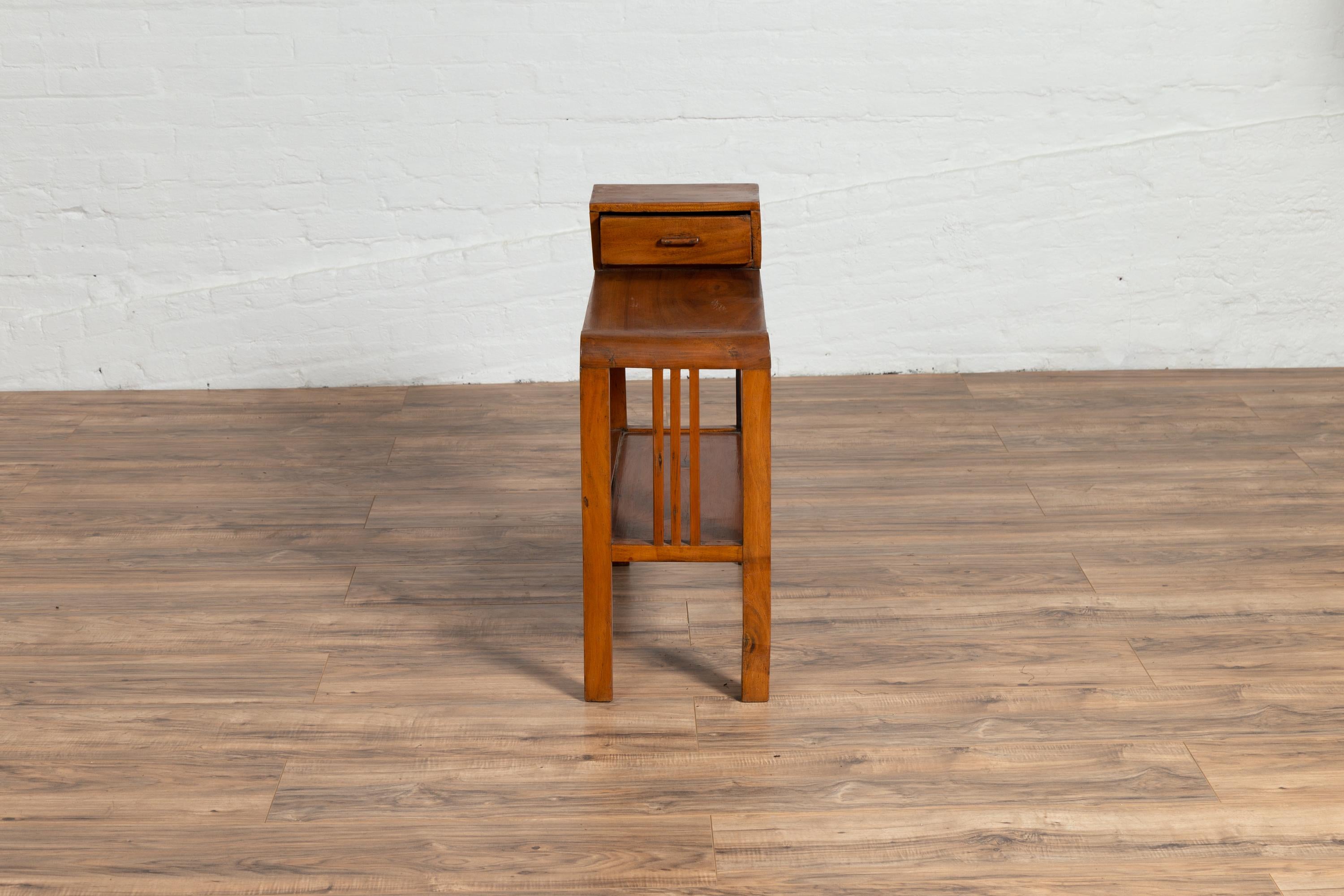 An Indonesian vintage Dutch Colonial side table from the mid-20th century, with single drawer, lower shelf and straight legs. Born in Indonesia during the mid-century period, this unusual side table features a single drawer, sitting above a narrow