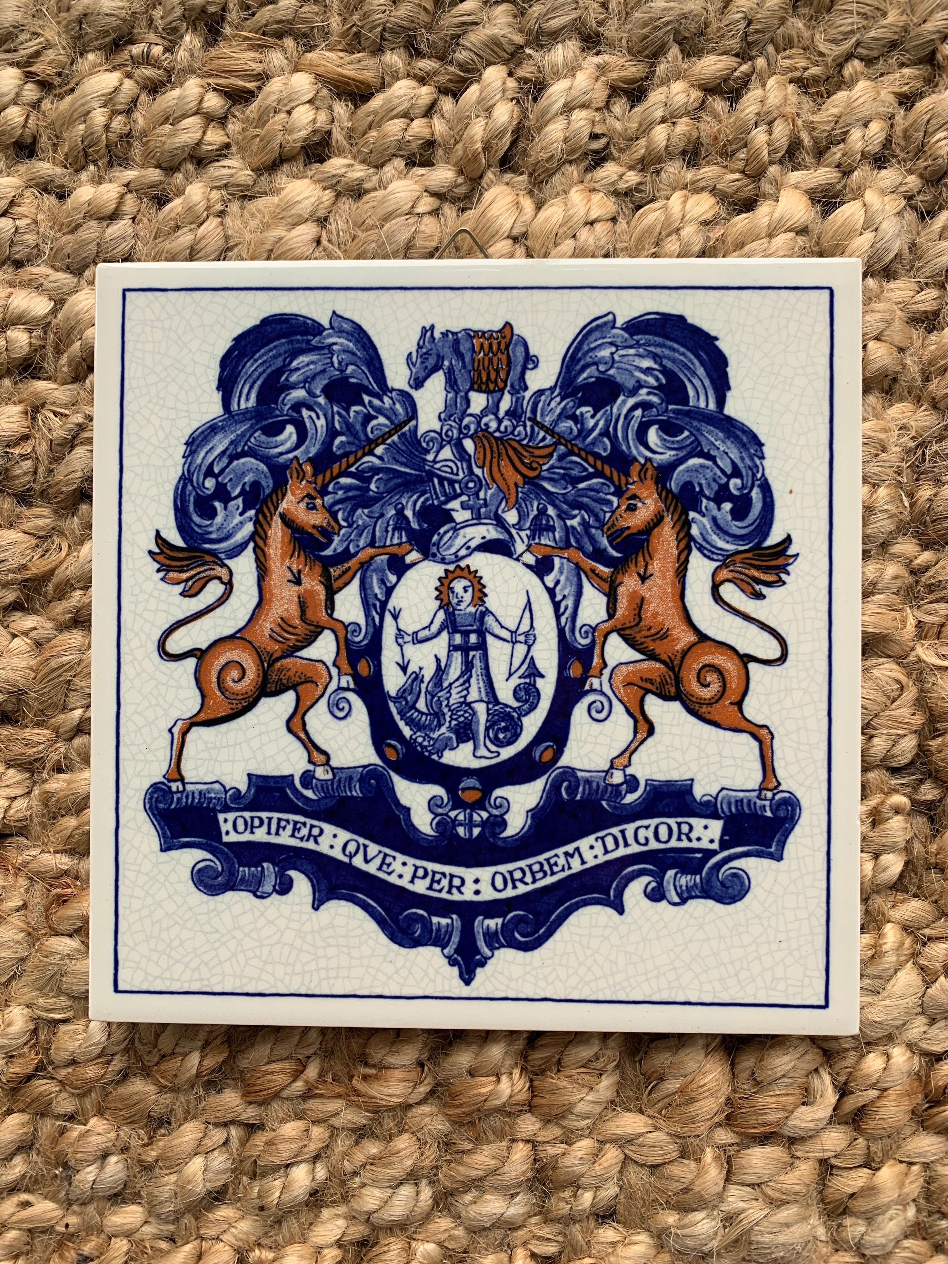 Magnifique carreau de céramique peint à la main en bleu et blanc, de style Delft ou provincial français, représentant une armure et un casque de chevalier stylisés, avec un rhinocéros au-dessus d'un bouclier avec deux licornes se faisant face. À