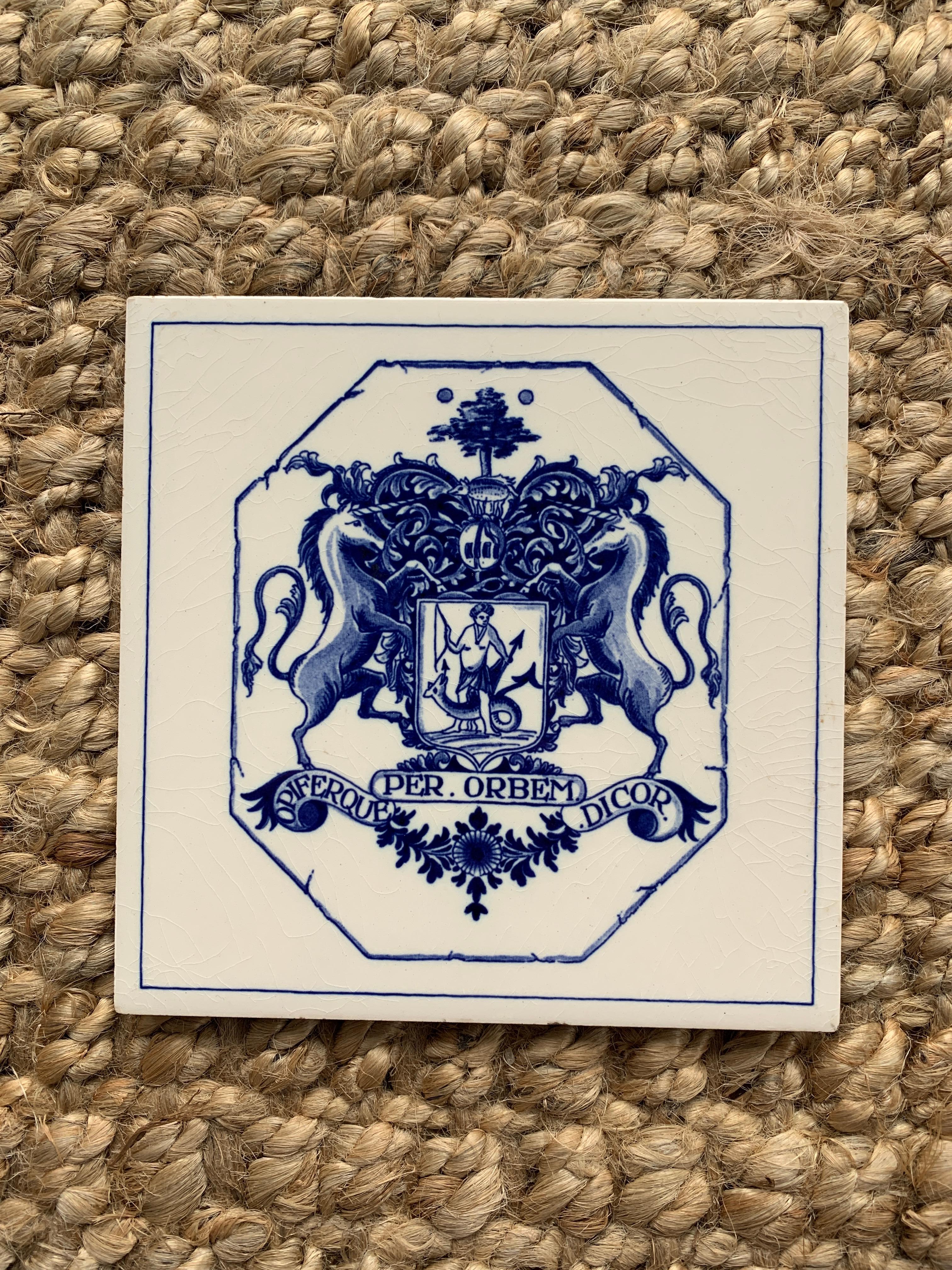 Magnifique carreau de céramique peint à la main en bleu et blanc, de style Delft ou provincial français, représentant une armure et un casque de chevalier stylisés, avec un rhinocéros au-dessus d'un bouclier avec deux licornes se faisant face. À