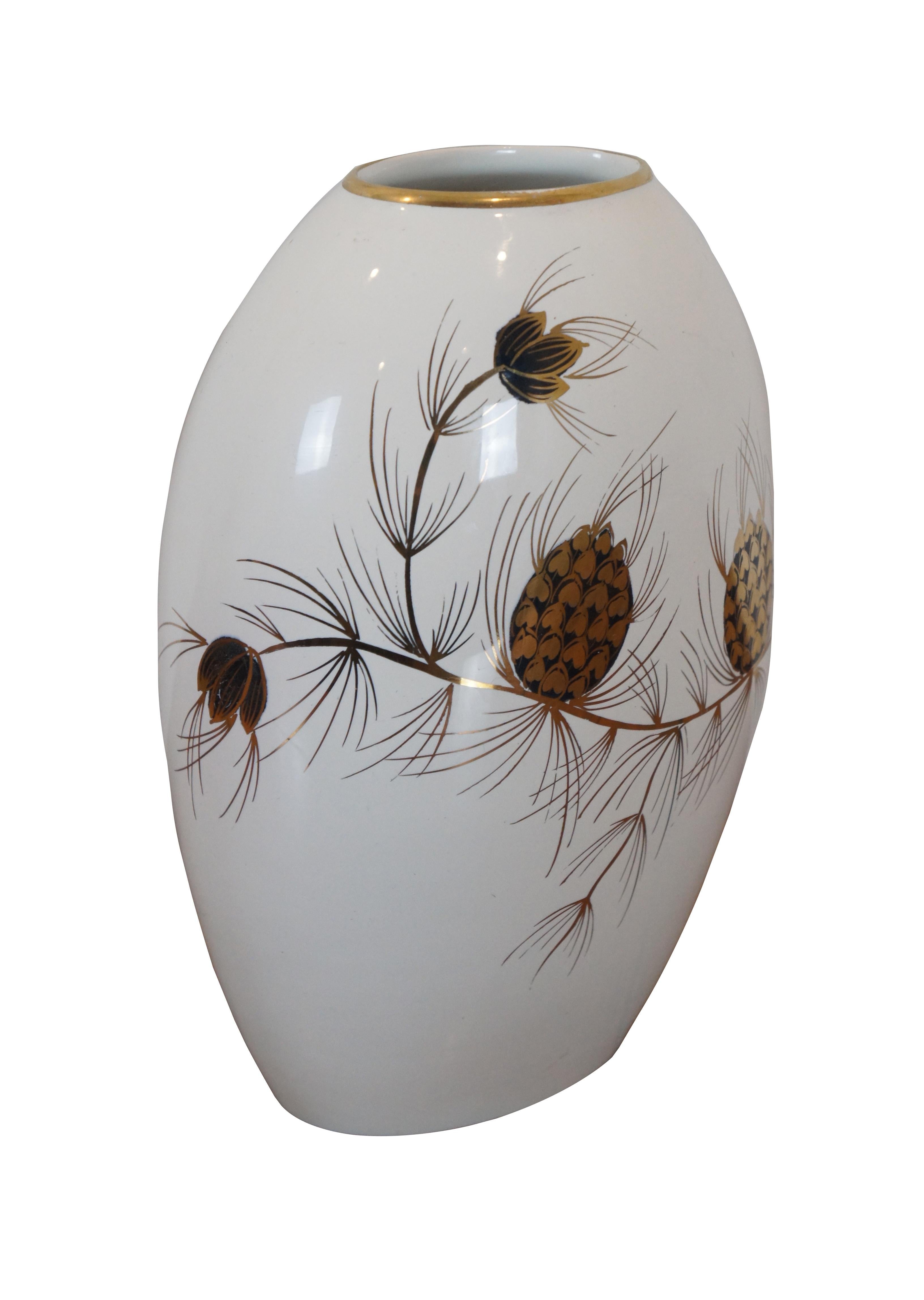 Vintage oval shaped, white porcelain vase decorated with a gilded and cobalt blue design of pine branches studded with cones. Marked on base: 921 – Dec: Denna – Flora Gouda Holland – Hand Painted.

Flora Holland - Gouda porcelain factory circa 1945