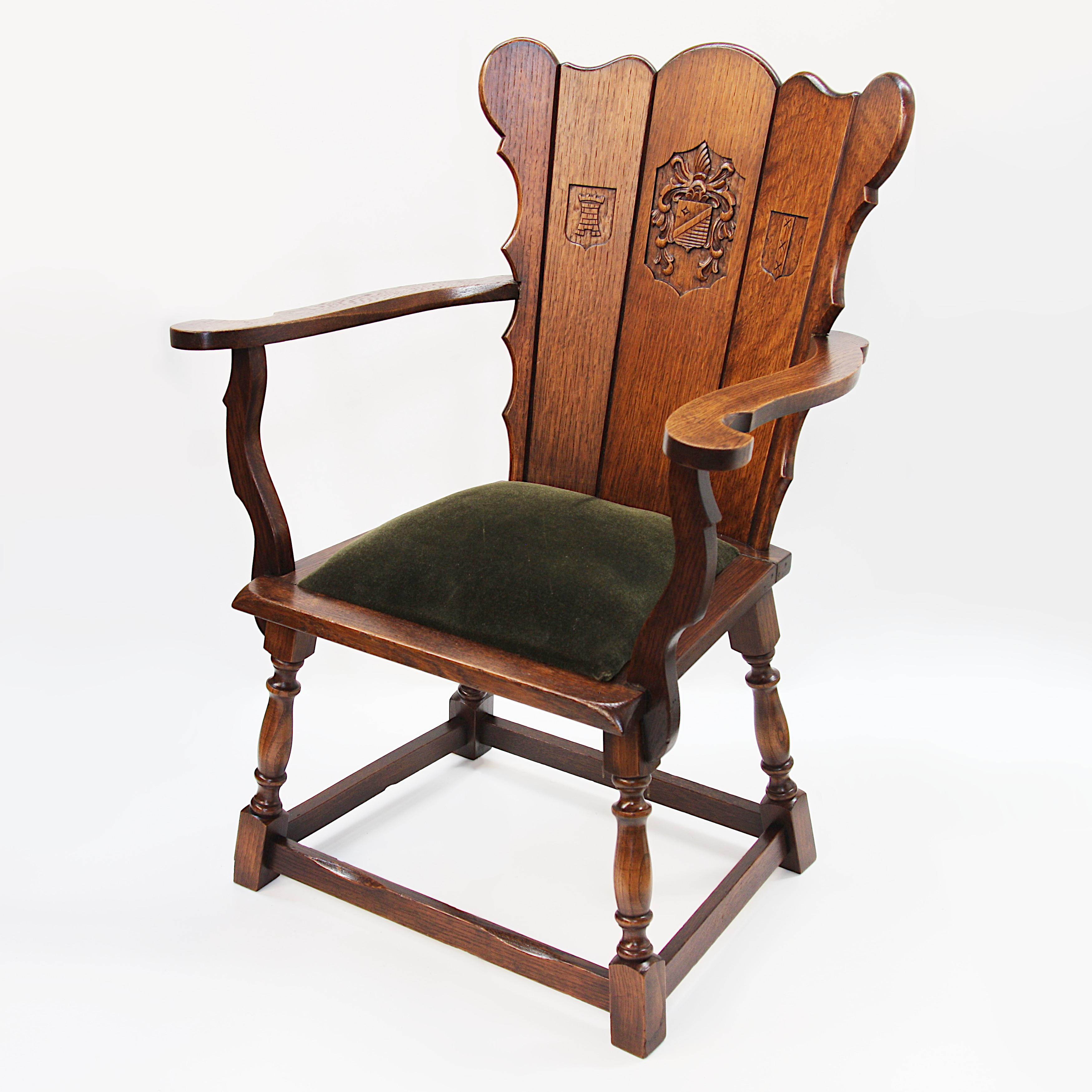 Wonderful early 20th century Dutch arm chair. Chair features solid oak construction, green mohair seat, and Classic medieval-revival design with relief-carved coats of arms. The right-side carving appears to be the Amsterdam coat of arms. The