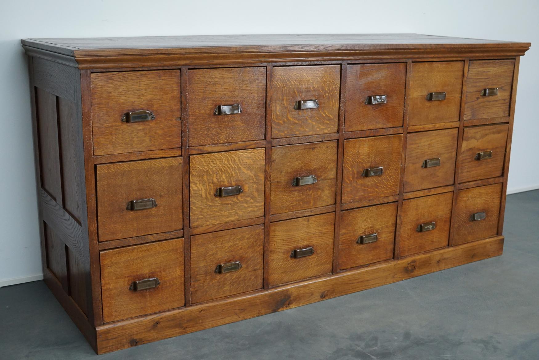This apothecary / filing cabinet was produced during the 1930s in the Netherlands. This piece features 18 large drawers. The interior dimensions of the drawers are: D x W x H 52 x 24 x 11 / 20 cm. They were used as filing cabinets in the town hall