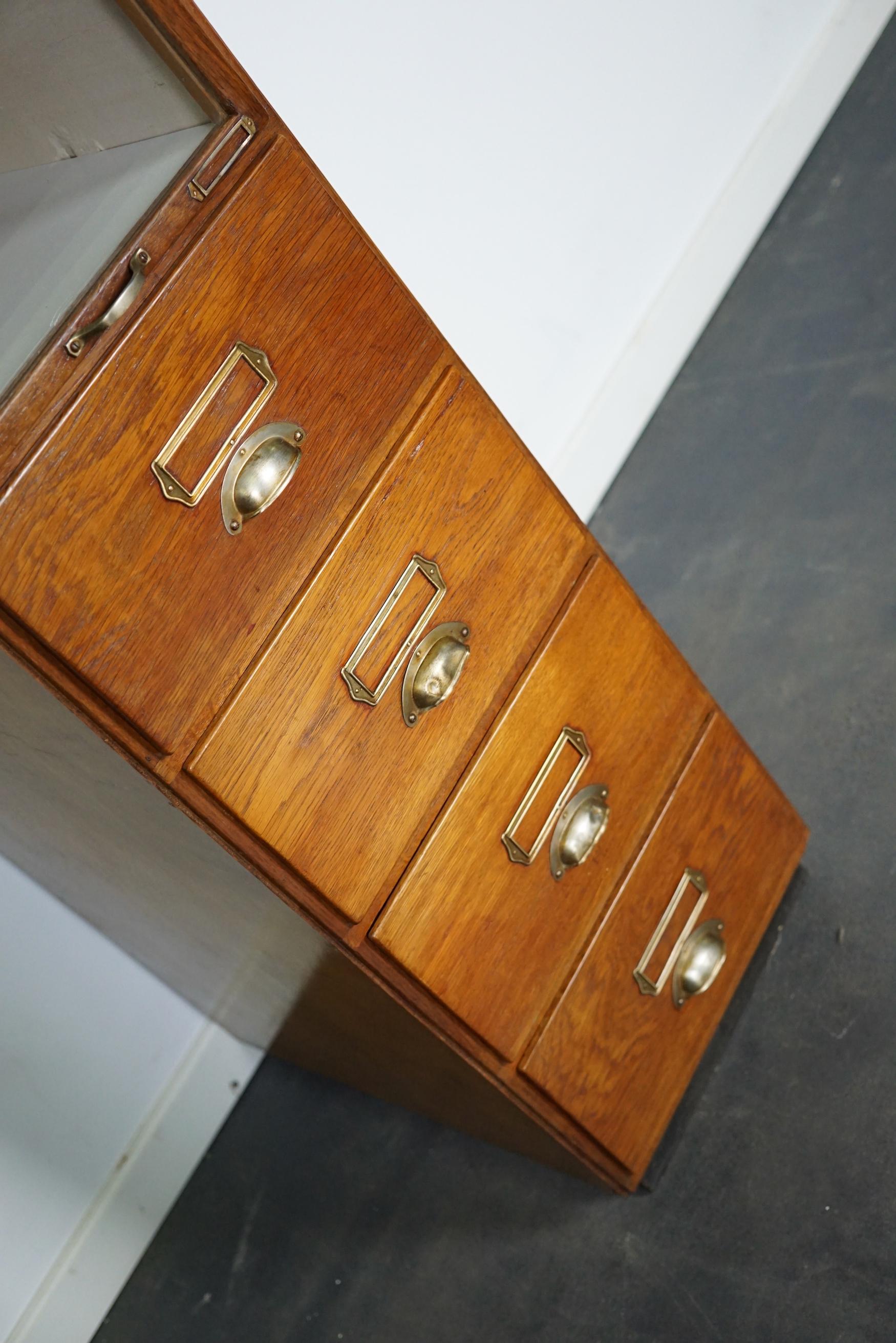 This haberdashery cabinet was produced during the 1930s in the Netherlands. This piece features 11 drawers in oak with or w/o glass fronts and metal handles. It was originally used in a shop for sewing supplies and fabrics in Amsterdam. The interior