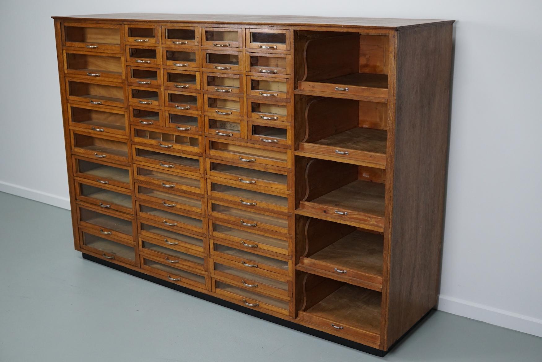 This haberdashery cabinet was produced during the 1930s in the Netherlands. It features many drawers in oak with glass fronts and metal handles. It was originally used in the department store Maussen in the city of Maastricht which was closed in