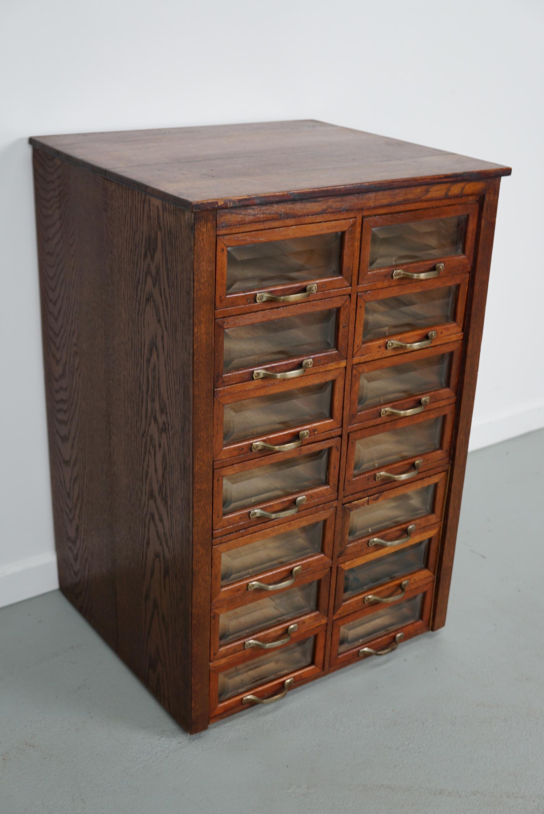 This haberdashery cabinet was produced during the 1930s in the Netherlands. It features 14 drawers in oak with cut glass fronts and metal handles. It was originally used in the department store Maussen in the city of Maastricht which was closed in