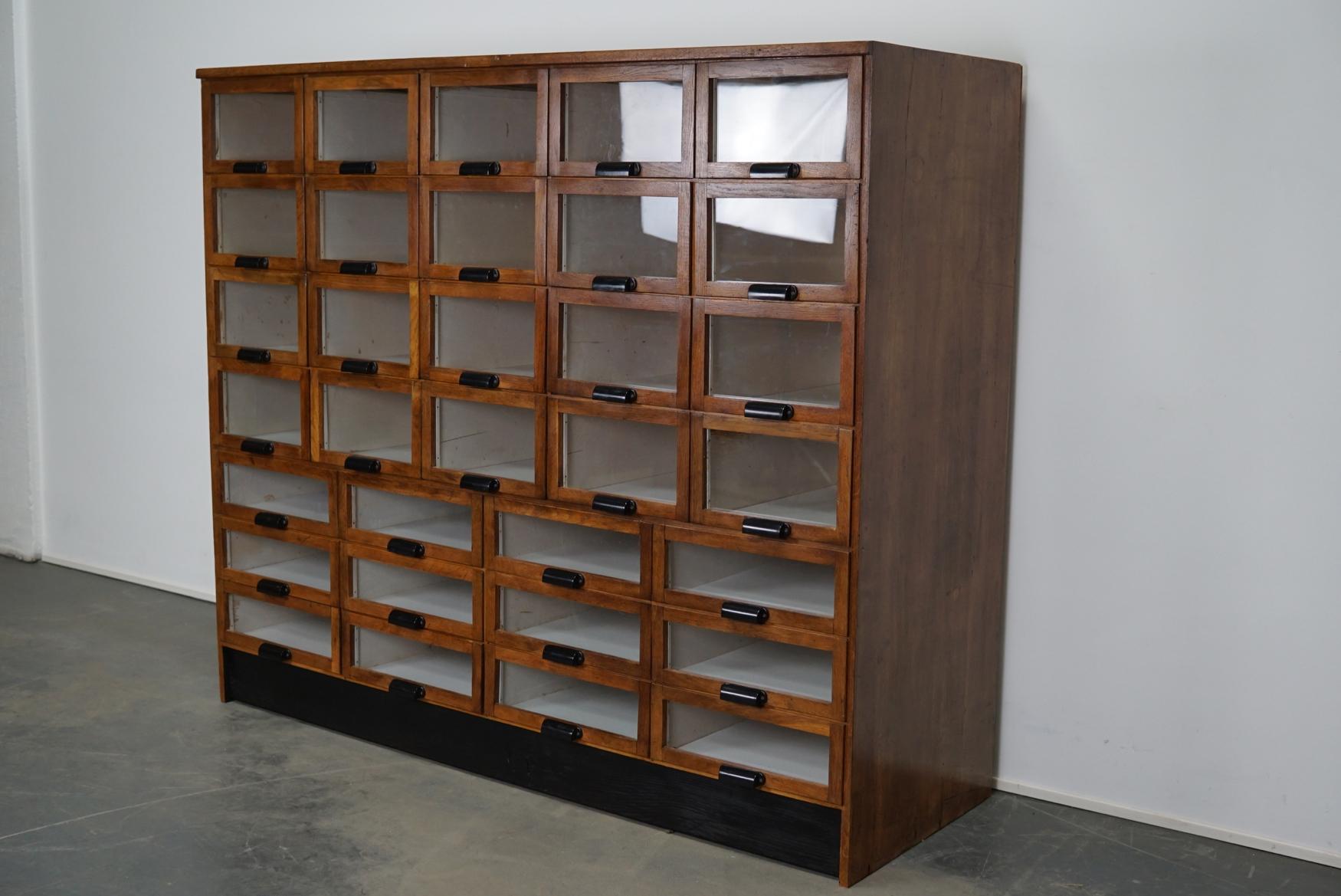 This haberdashery cabinet was produced during the 1950s in the Netherlands. This piece features 32 drawers with glass fronts and Bakelite handles. It was originally used in a shop for sewing supplies and fabrics. The interior dimensions of the