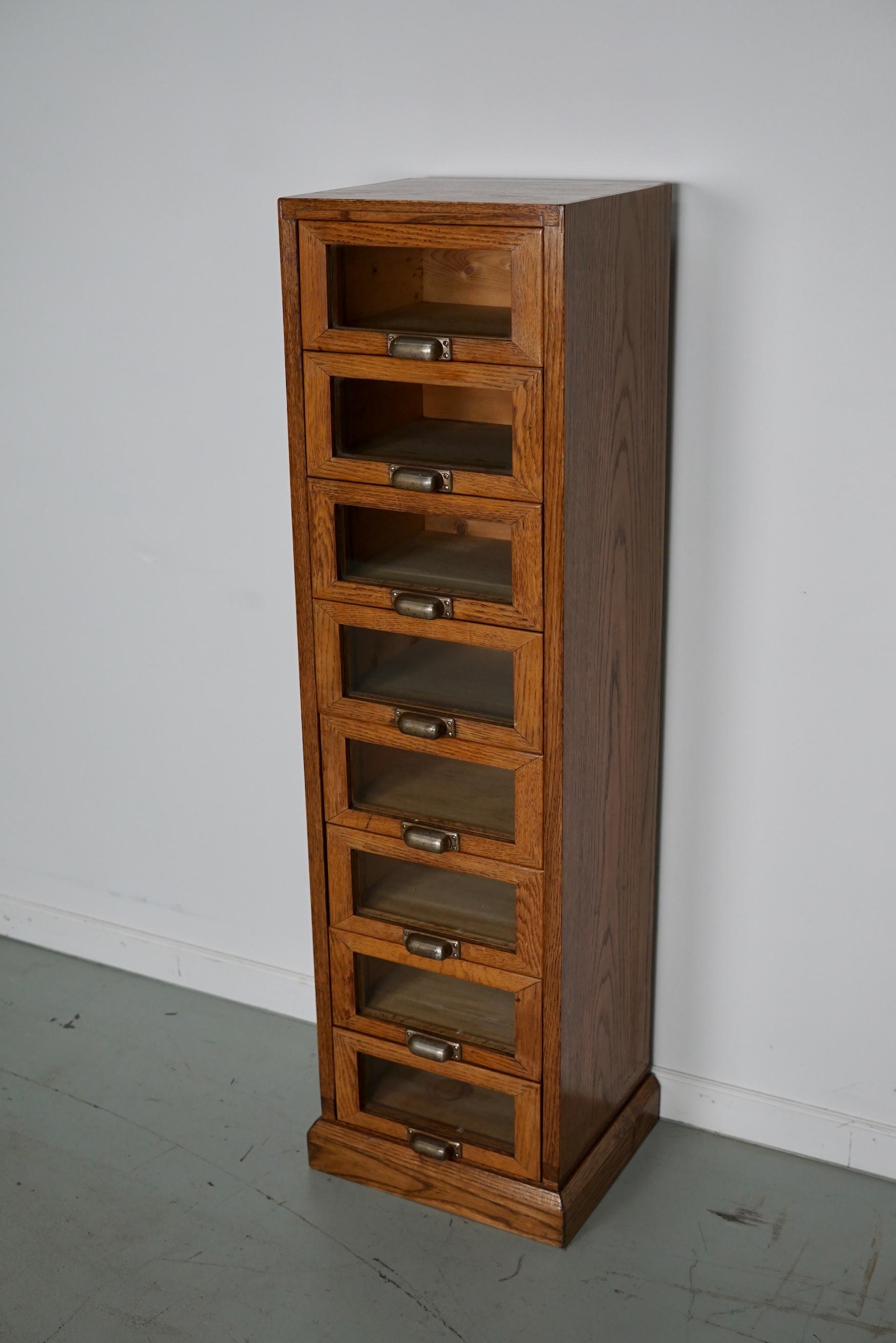 This haberdashery cabinet was produced during the 1950s in the Netherlands. This piece features 8 drawers in light oak with glass fronts and metal handles. It was originally used in a shop for sewing supplies. The interior dimensions of the drawers