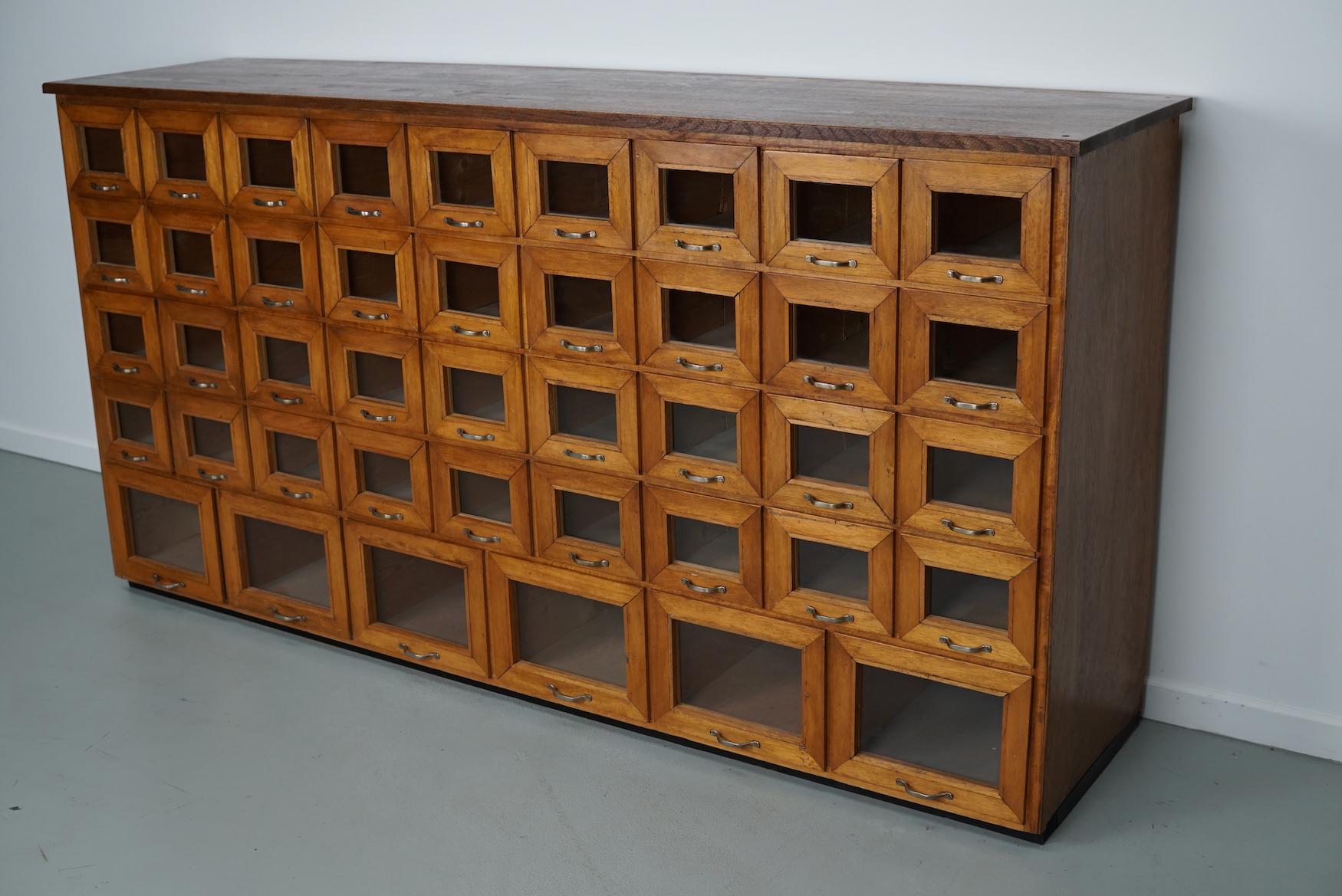 This haberdashery cabinet was produced during the 1950s in the Netherlands. It features 42 drawers in oak with glass fronts and metal handles. It was originally used in a warehouse for plant seeds in the city of Delft. The interior dimensions of the