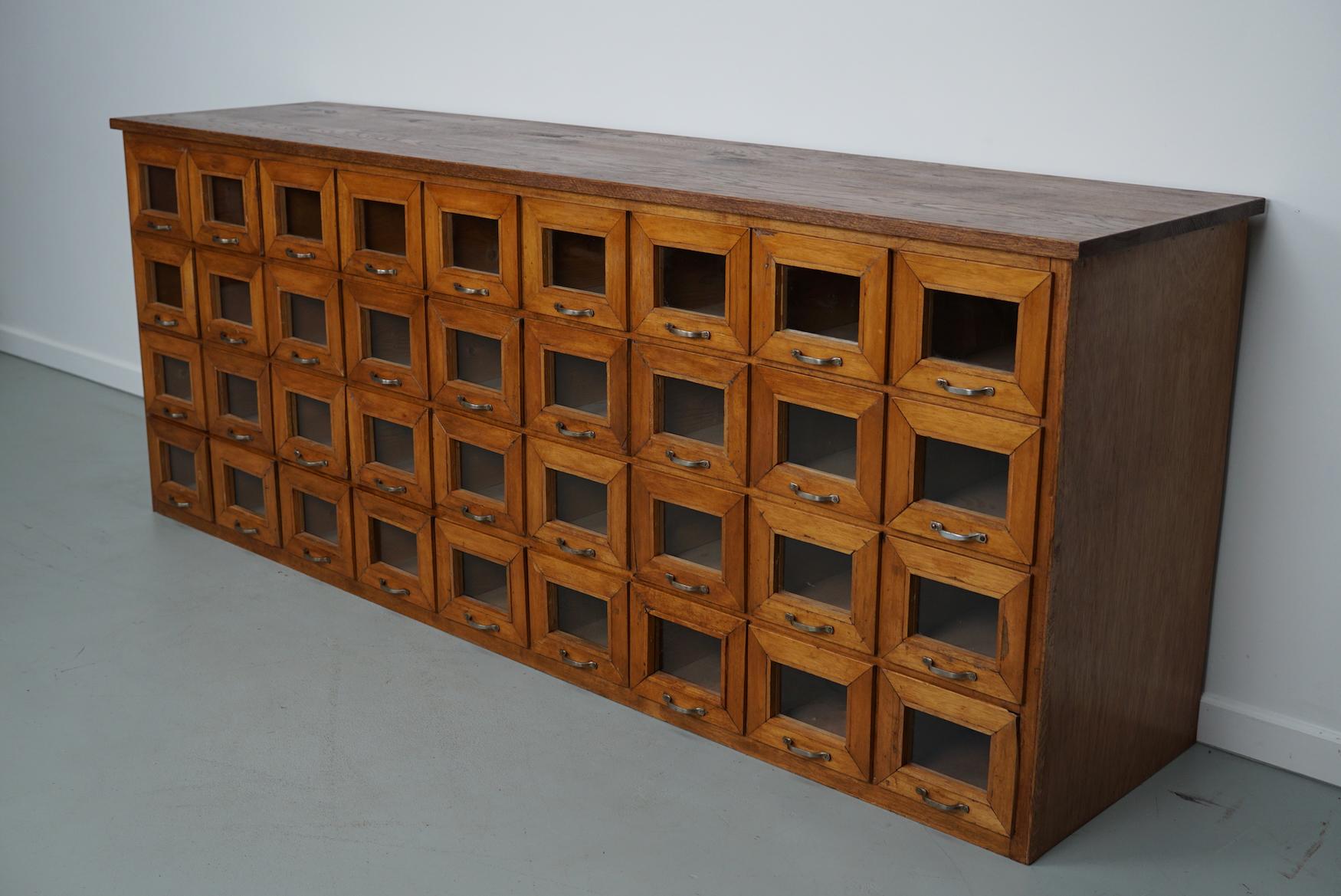 This haberdashery cabinet was produced during the 1950s in the Netherlands. It features 36 drawers in oak with glass fronts and metal handles. It was originally used in a warehouse for plant seeds in the city of Delft. The interior dimensions of the