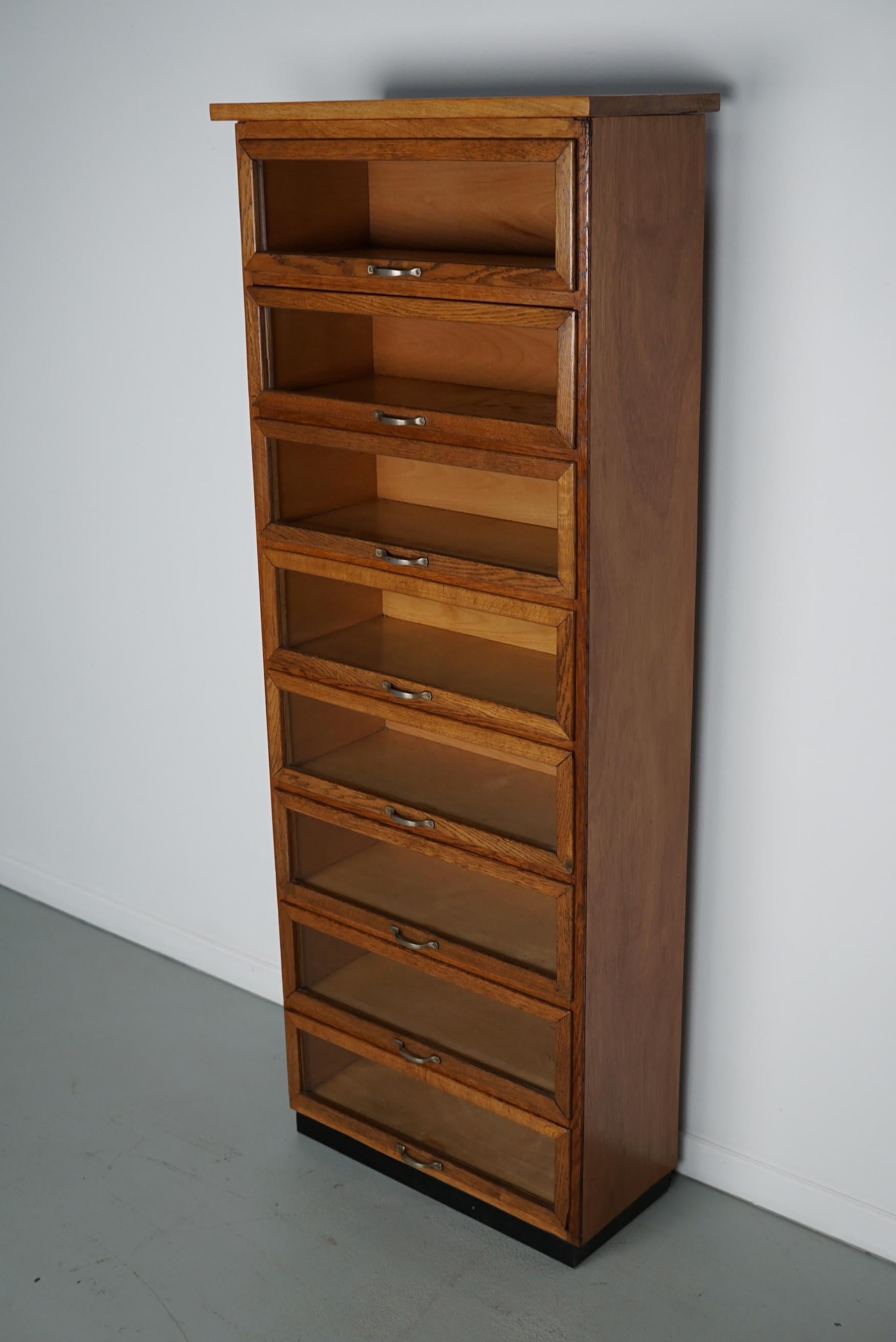 Questo mobile da merceria è stato prodotto negli anni '1950 nei Paesi Bassi. Dispone di 8 ampi cassetti in Oak con frontali in vetro e maniglie in metallo. In origine era utilizzato in un negozio di lingerie. Le dimensioni interne dei cassetti sono: