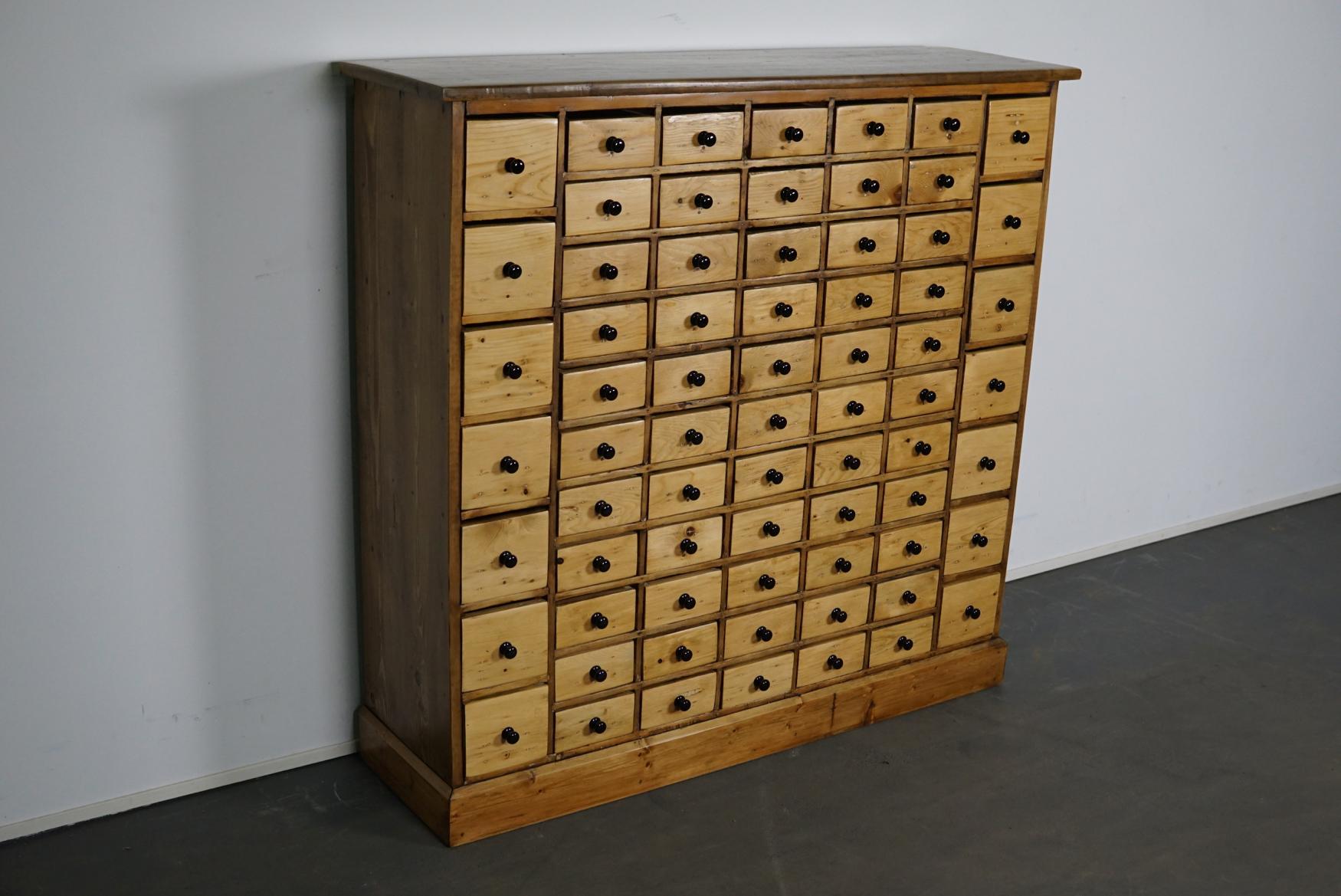 This apothecary cabinet of drawers was designed, circa 1950s in the Netherlands. The piece is made from pine and features 69 drawers with black knobs. The interior dimensions of the drawers are: D 25 x W 11 x H 10.5 and 6 cm.