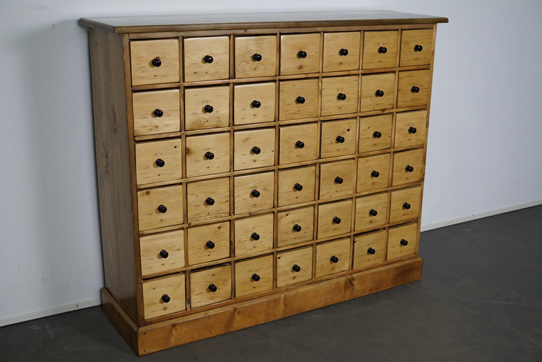 This apothecary cabinet of drawers was designed, circa 1950s in the Netherlands. The piece is made from pine and features 42 drawers with black knobs. The interior dimensions of the drawers are: D 25 x W 11.5 x H 10.5 cm.