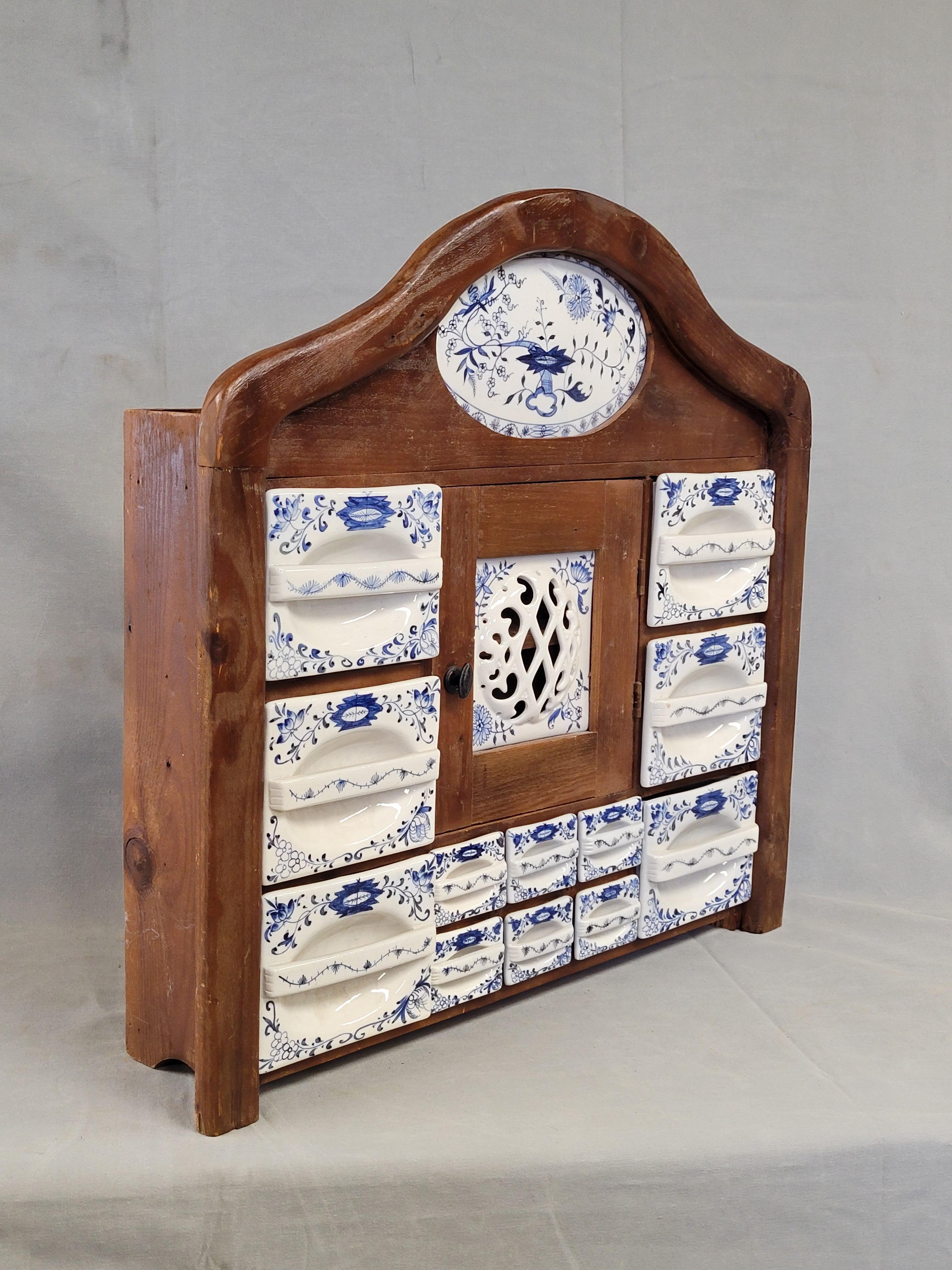 A charming vintage Dutch kitchen spice rack is made of wood and has ceramic blue and white (blue onion pattern) drawer inserts. The cabinet door opens for fresh egg storage (in Europe fresh eggs are not refrigerated). Can be hung on a wall, built